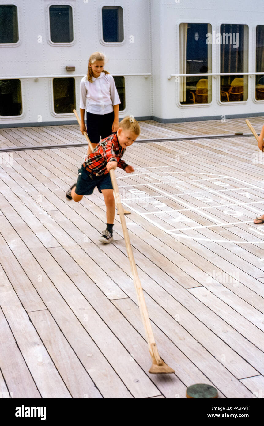 Bambini, fratello e sorella, una ragazza e un ragazzo che giocano a shuffleboard sulla SS Rotterdam Ocean Liner, Holland America Line negli anni '60 Foto Stock