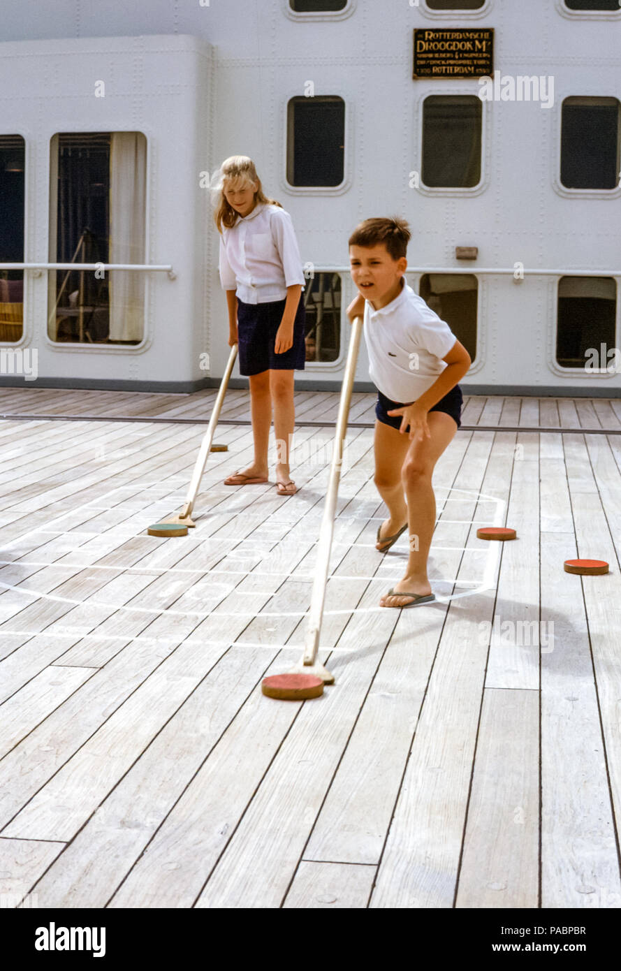 Bambini, fratello e sorella, una ragazza e un ragazzo che giocano a shuffleboard sulla SS Rotterdam Ocean Liner, Holland America Line negli anni '60 Foto Stock