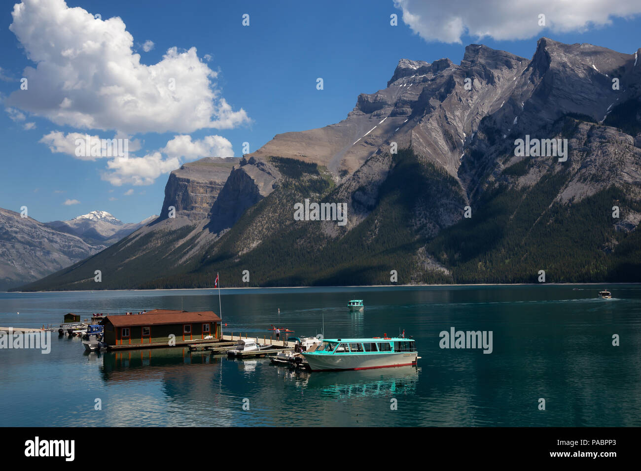 Imbarcazioni presso il dock con una bella canadese paesaggio di montagna in background. Presi nel Lago Minnewanka, Banff, Alberta, Canada. Foto Stock