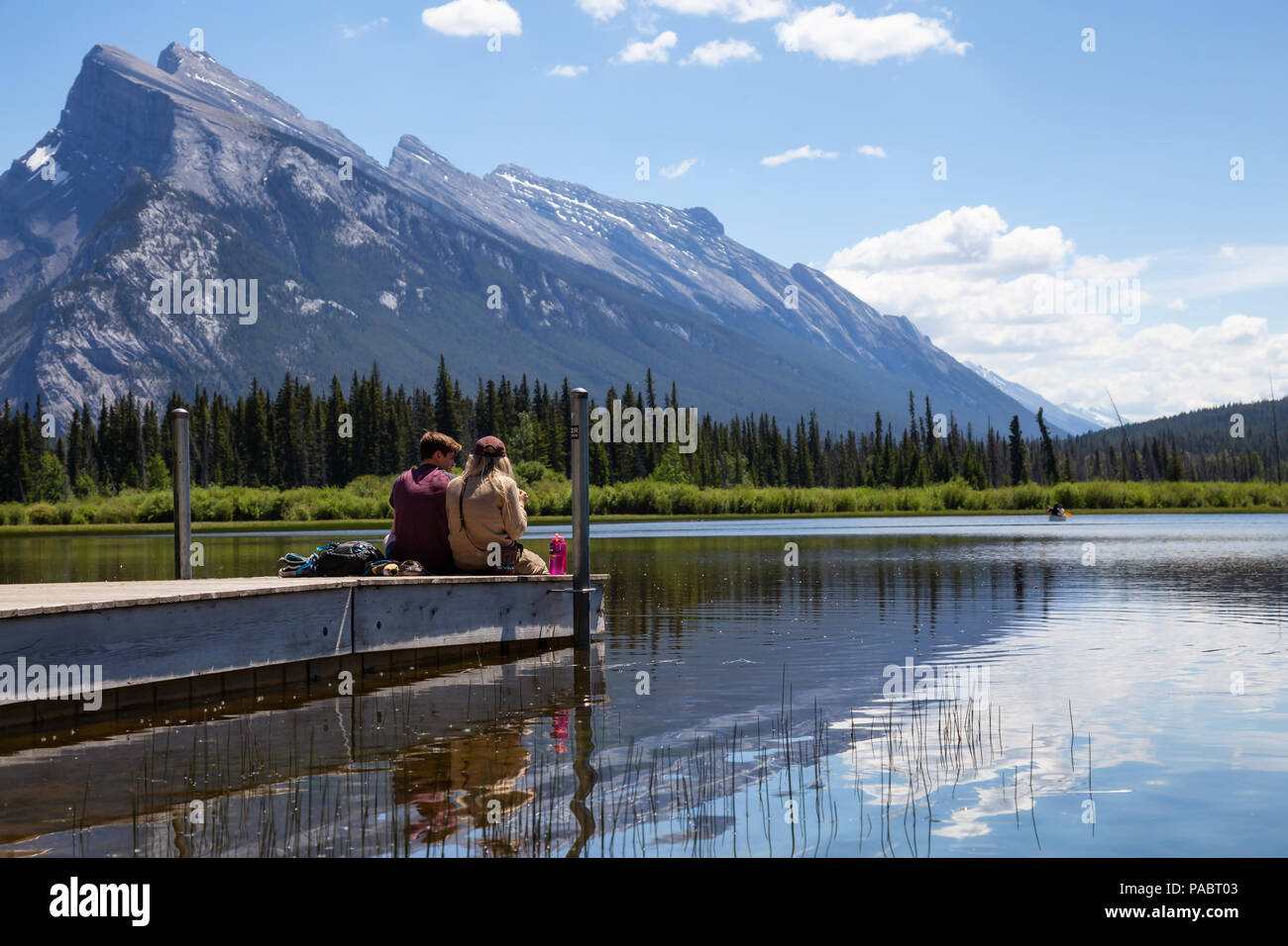 Banff, Alberta, Canada - 19 Giugno 2018: giovane amici stanno godendo della splendida vista su un dock in legno. Foto Stock