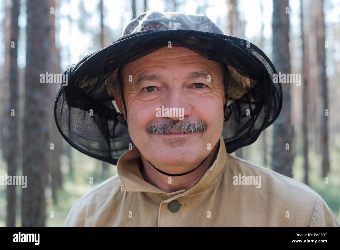 Closeup ritratto di un uomo anziano in speciali hat contro la zanzara in piedi nella foresta. Foto Stock