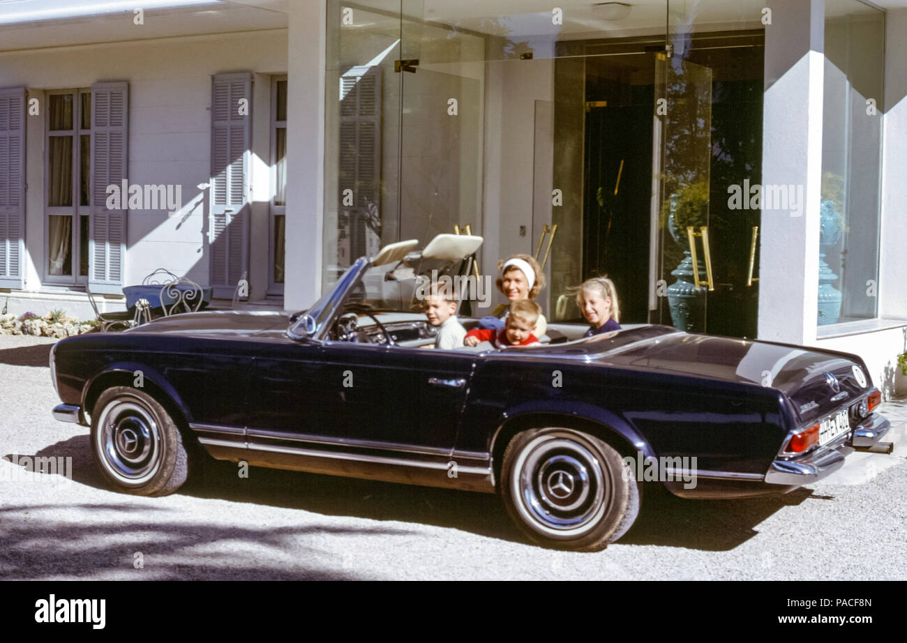 Famiglia con donna e tre bambini seduti in 1964 Mercedes-Benz 230SL auto sportiva convertibile di fronte all'hotel a Grasse, Francia negli anni '60 Foto Stock