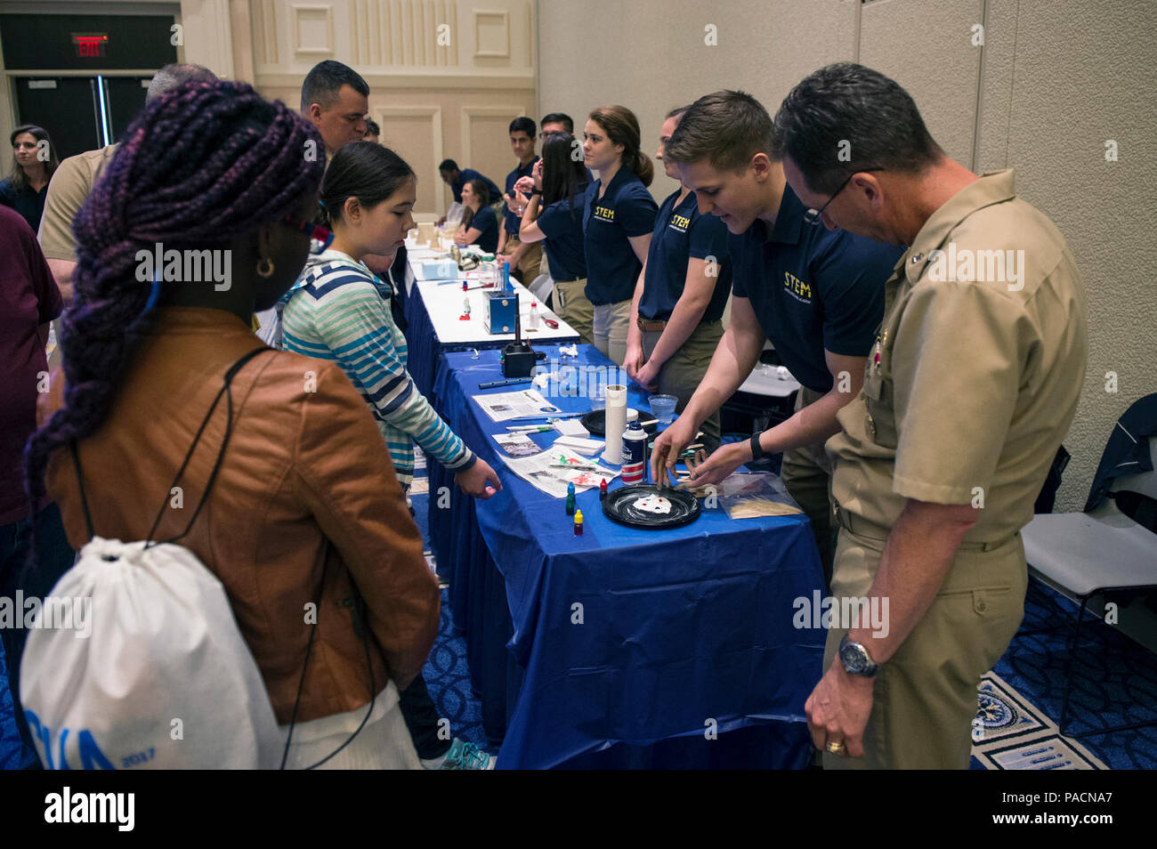 Il porto nazionale, Md. (apr. 2, 2017) posteriori Adm. David Hahn, capo del Naval Research, guarda come Guardiamarina di terza classe Winkie Mitchell conduce un esperimento durante il 2017 stelo navale Exposition, co-sponsorizzata dalla Lega Navale degli Stati Uniti e l'Ufficio del Naval Research (ONR). La manifestazione offre attività pratiche e fornisce la scuola media e superiore agli studenti un'introduzione a stelo navale di carriera e opportunità educative. Foto Stock