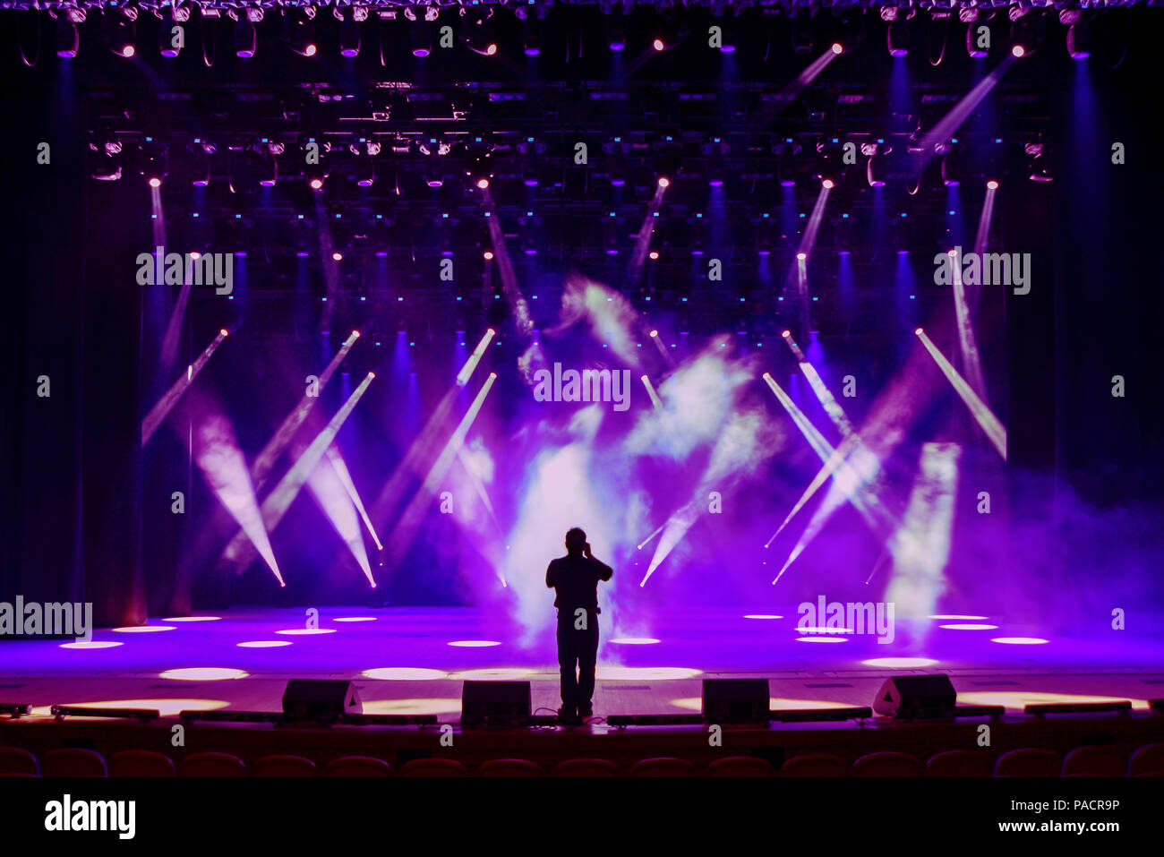 Il canto dell'uomo sulla silhouette di una luminosa fase di concerto contro lo sfondo di raggi di intradossi e scenic nebbia Foto Stock Il canto dell'uomo sulla silhouette di una luminosa fase di concerto contro lo sfondo di raggi di intradossi e scenic nebbia Foto Stock