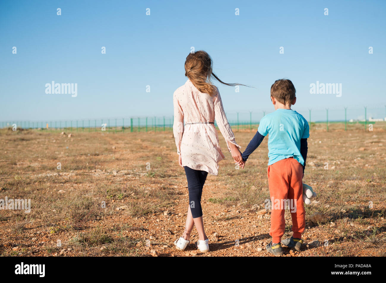 Piccolo fratello e sorella di profughi tenendo le mani piedi tra deserto sul confine Foto Stock