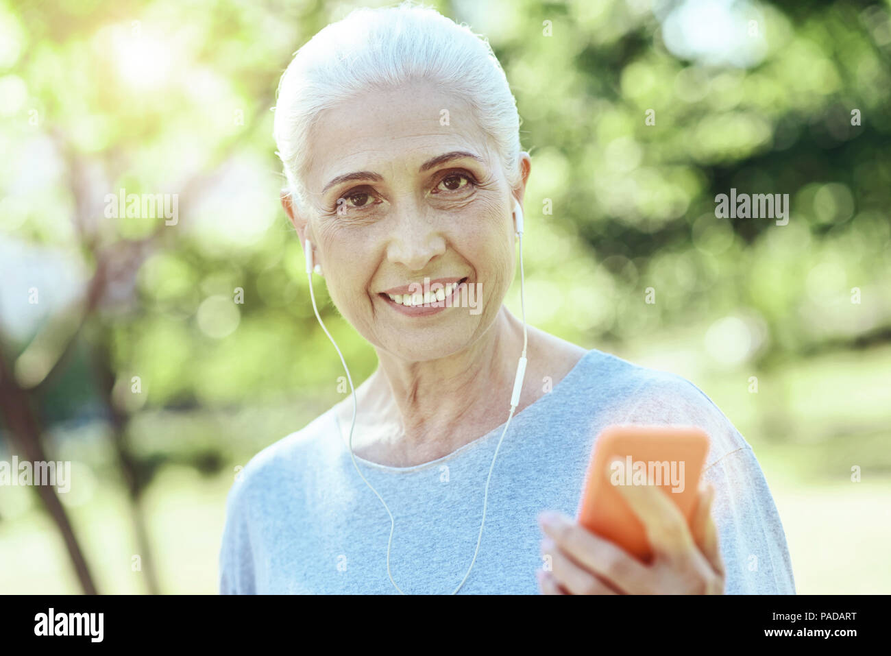 Allegro anziani donna che indossa gli auricolari Foto Stock