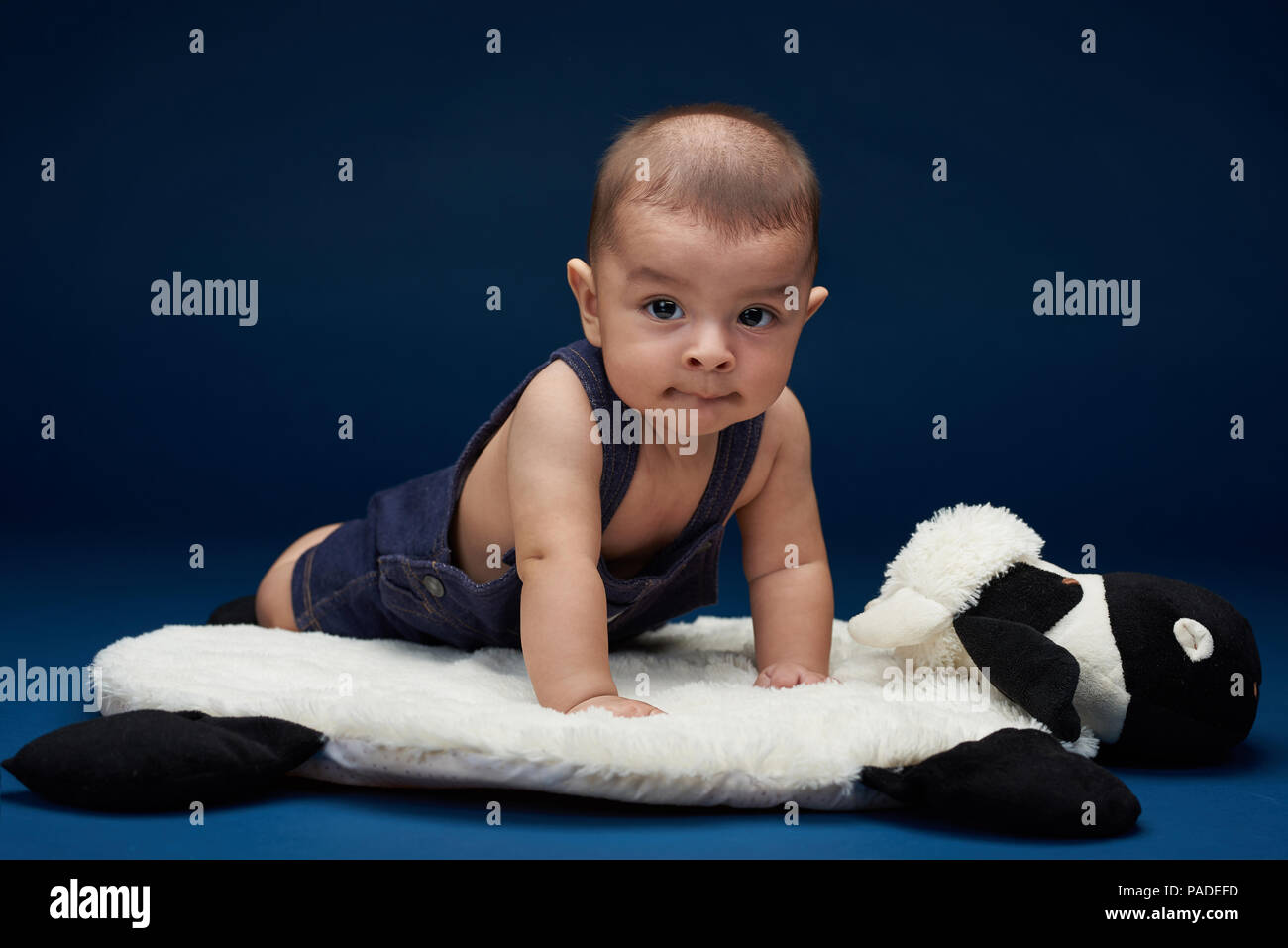 Piccolo bambino seduto sul cuscino e guarda nella telecamera Foto Stock
