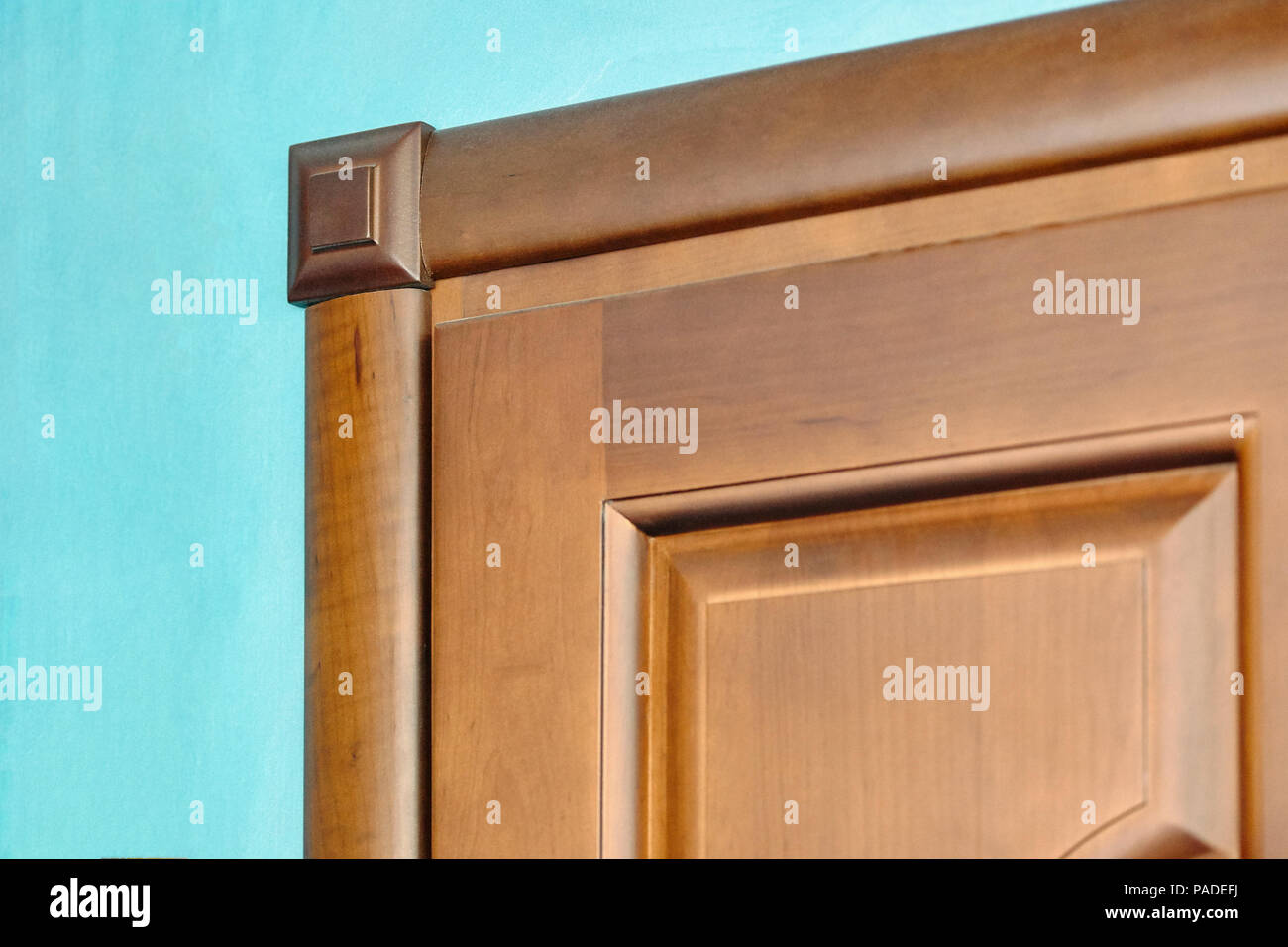 Elemento della porta di legno in cornice di legno marrone intagliato addobbi geometrici di stile classico blu sul muro intonacato background close up Foto Stock