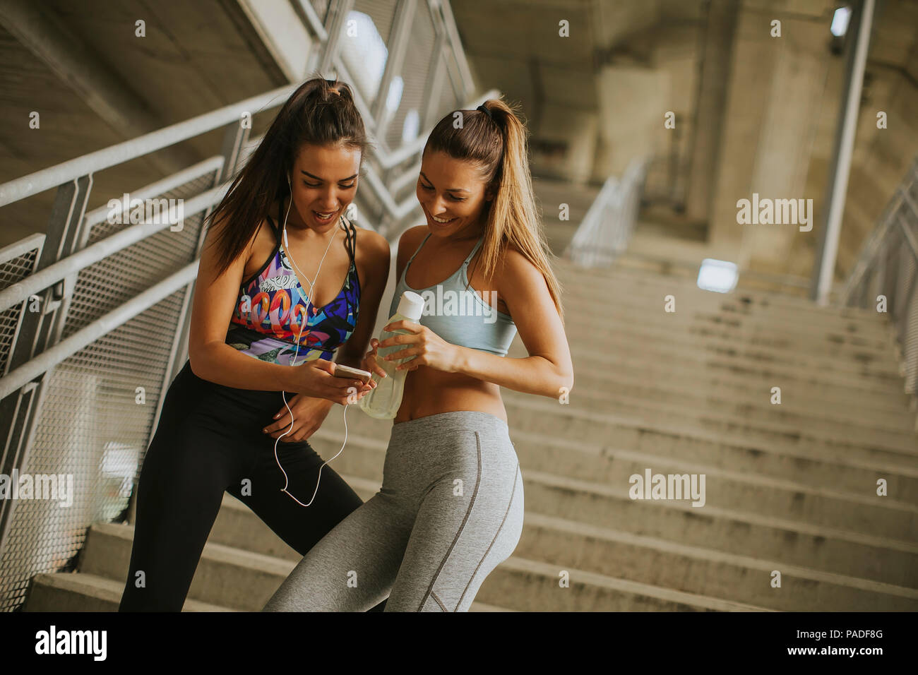 Due guide femmina cerca su smart phone un riposo dopo un po' di jogging nel envionment urbana Foto Stock