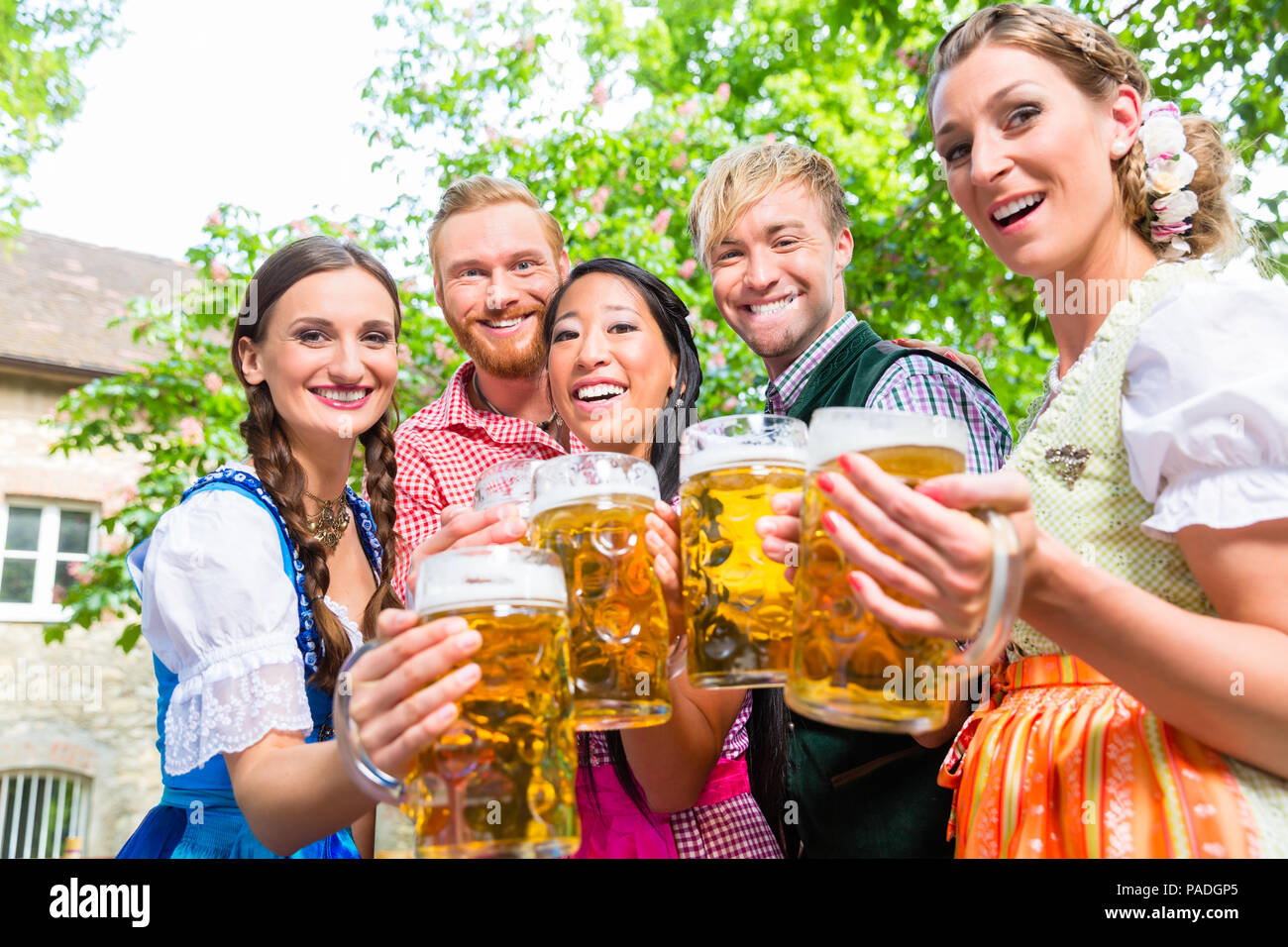 Amici divertendosi nel giardino della birra mentre bicchieri tintinnanti Foto Stock