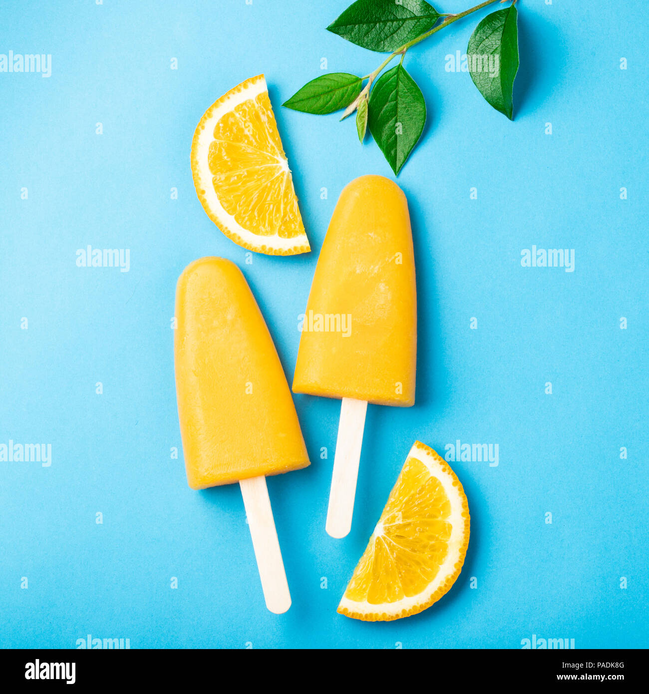 Popsicles arancione con il succo su uno sfondo blu. Ice pops, piatto di laici che, vista dall'alto. Foto Stock