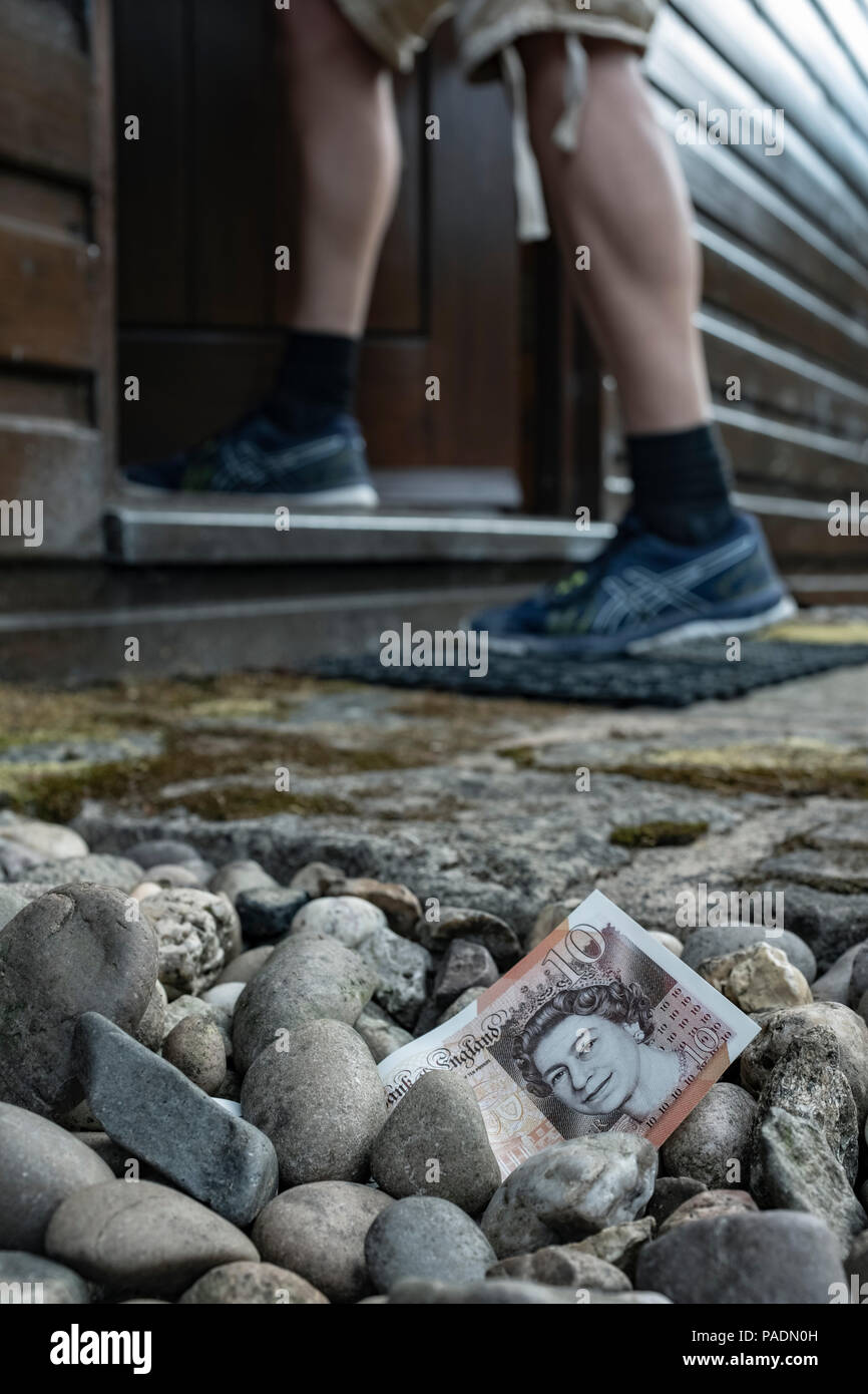 Il denaro nella forma di una banca nota sul terreno al di fuori di una casa. Foto Stock