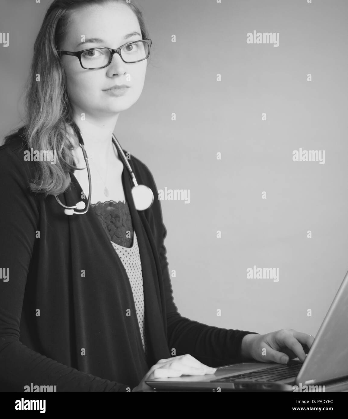 Attraente giovane donna che indossa lo stetoscopio e la digitazione sul computer portatile Foto Stock