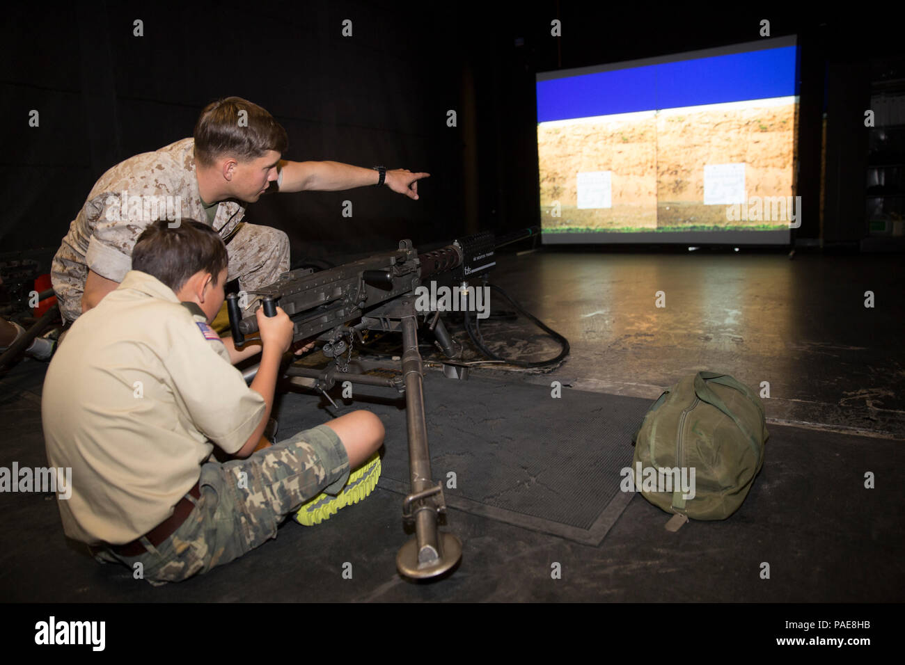 Lancia Cpl. Christopher Bailey, assaultman, 3° Battaglione, 7° Reggimento Marine, dirige il fuoco come Devin Castanon, 12, boy scout, truppa 72, si prepara a fuoco un M240B Mitragliatrice all'interno simulato precisione di tiro Trainer durante il Boy Scout Camp per local Boy Scouts of America truppe Marzo 18, 2016. (Gazzetta Marine Corps foto di Sgt. Charles Santamaria/rilasciato) Foto Stock