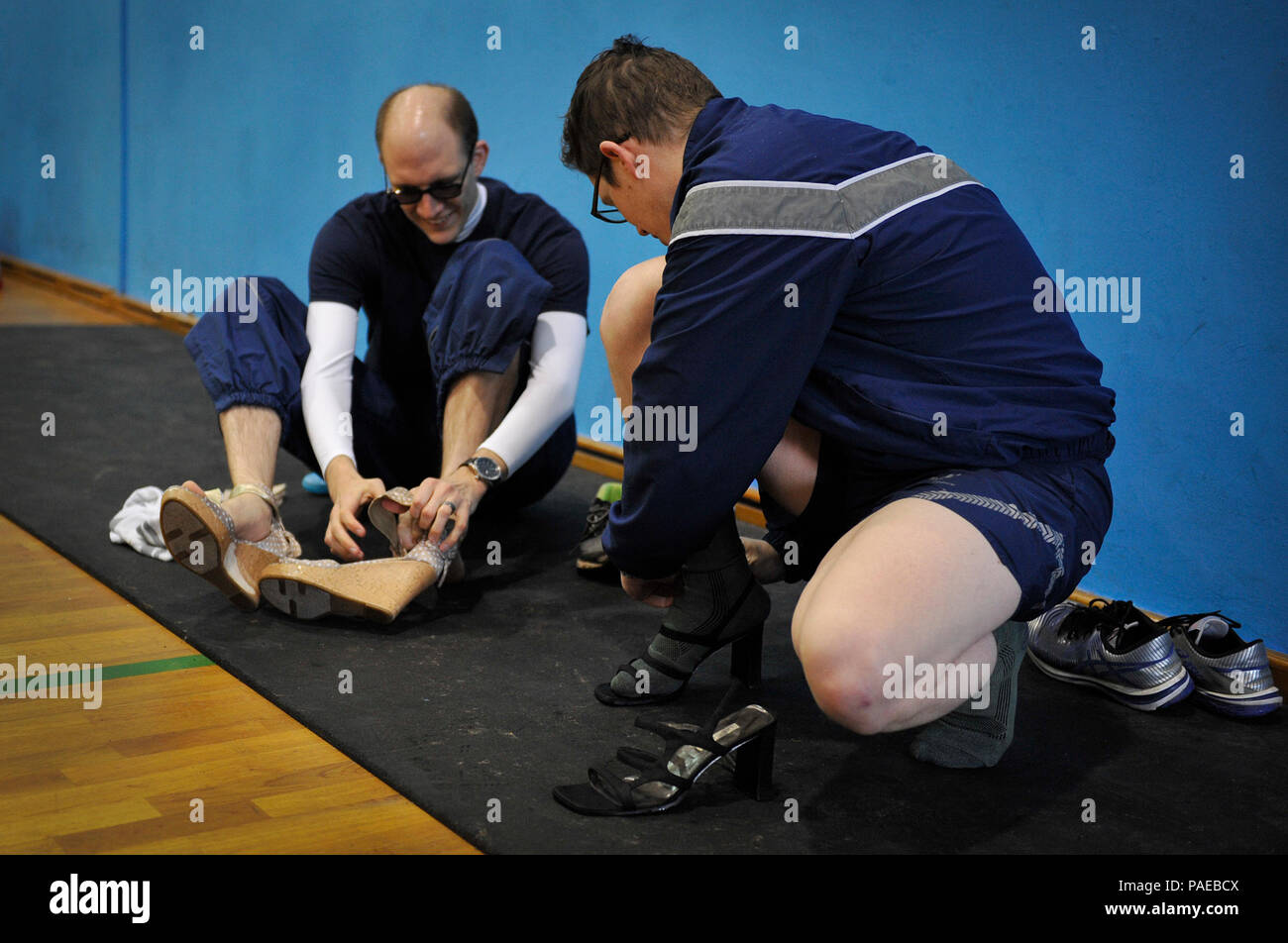 Il cap. Amos Gregorio (sinistra), 86Airlift Wing giudice avvocato capo di assistenza giuridica e il diritto di prevenzione e il cap. Justin Haselden, 86AW Giudice avvocato responsabile della legge generale, mettere su tacchi alti prima della prima un miglio a piedi nei suoi talloni e 5K eseguire Marzo 25, 2016 a Ramstein Air Base, Germania. Gli uomini e le donne hanno partecipato all'evento che simboleggiava la difficoltà incontrano le donne soprattutto in una società dominata da maschi. (U.S. Air Force foto/Airman 1. Classe Larissa Greatwood) Foto Stock
