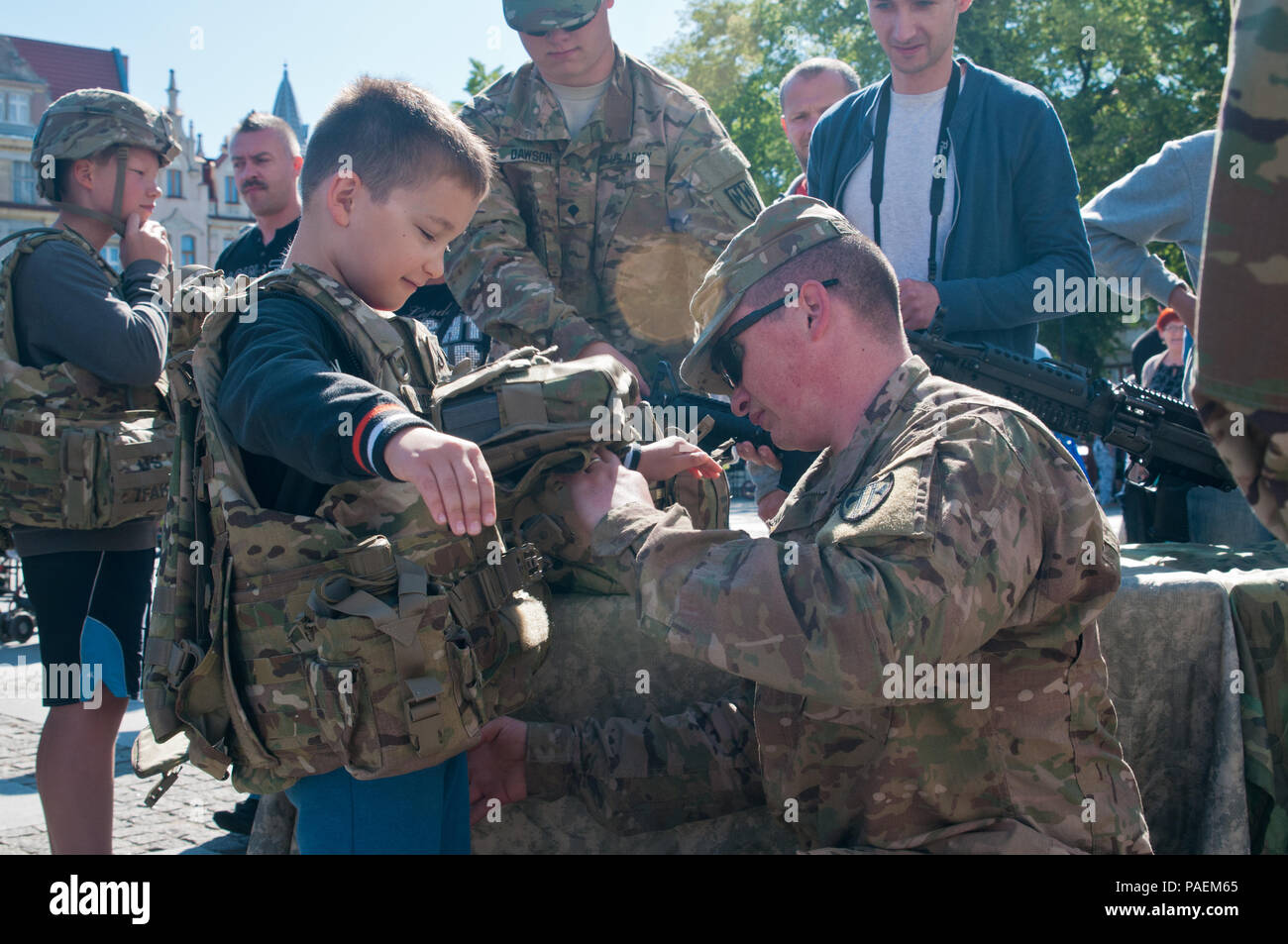 Sgt. Pieter Vernon, un Appleton, Wisconsin, nativo, con la XVIII Polizia Militare Brigata aiuta un bambino polacco suit fino in esterno migliorato gilet tattico durante la visualizzazione statica a giornata multiculturale evento nella piazza della città di Chelmno, Polonia, come una parte di esercizio Anakonda 2016. Esercizio Anakonda 2016 è il principale evento di formazione per gli Stati Uniti Esercito e l'Europa delle nazioni partecipanti e dimostra come gli Stati Uniti e i paesi partner possono efficacemente unità insieme sotto un comando unificato mentre la formazione su un scenario contemporaneo. Foto Stock