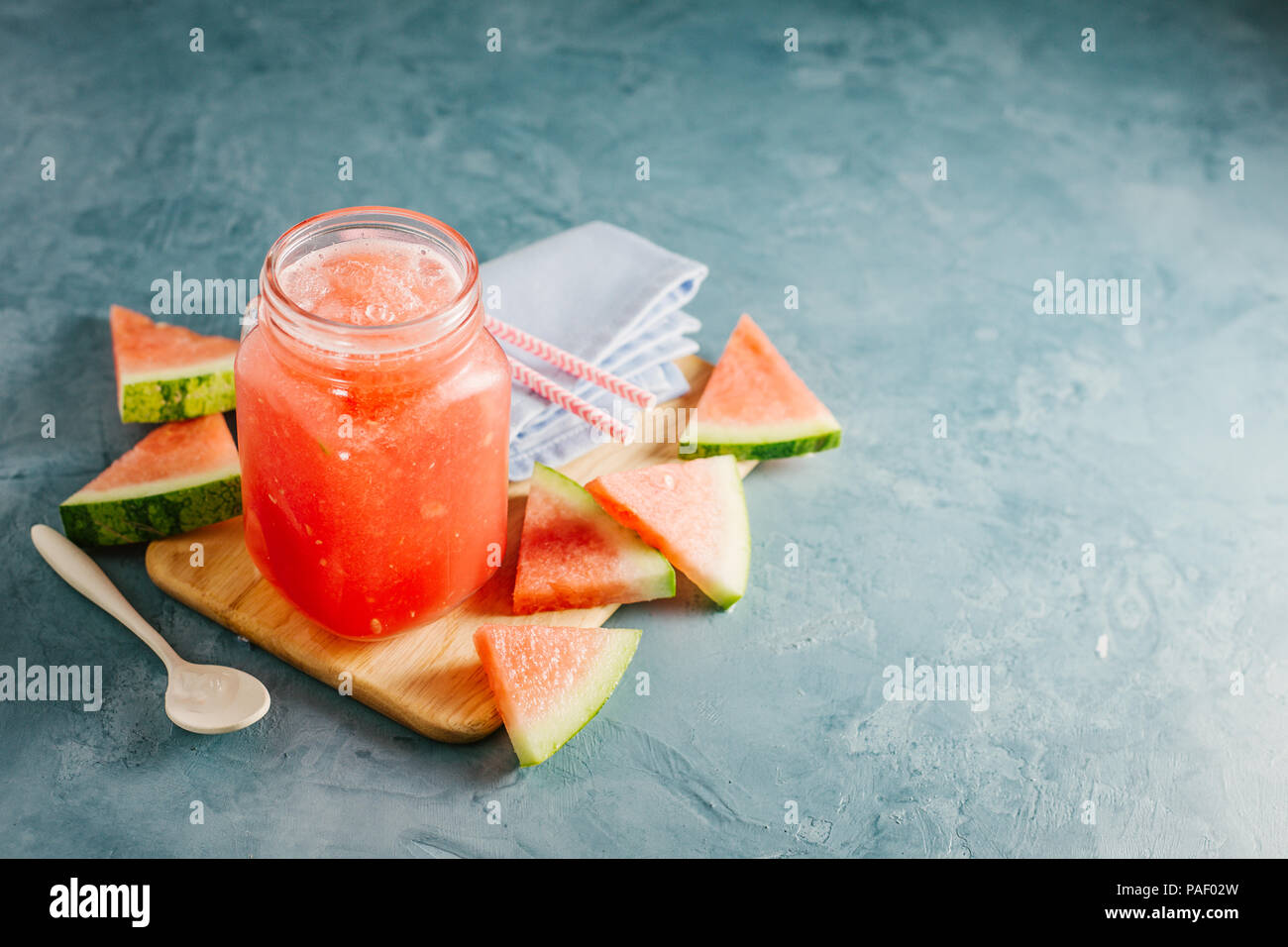 Freddo fresco cocomero bevande con ghiaccio e fette di cocomero sul tavolo blu. Primo piano Foto Stock