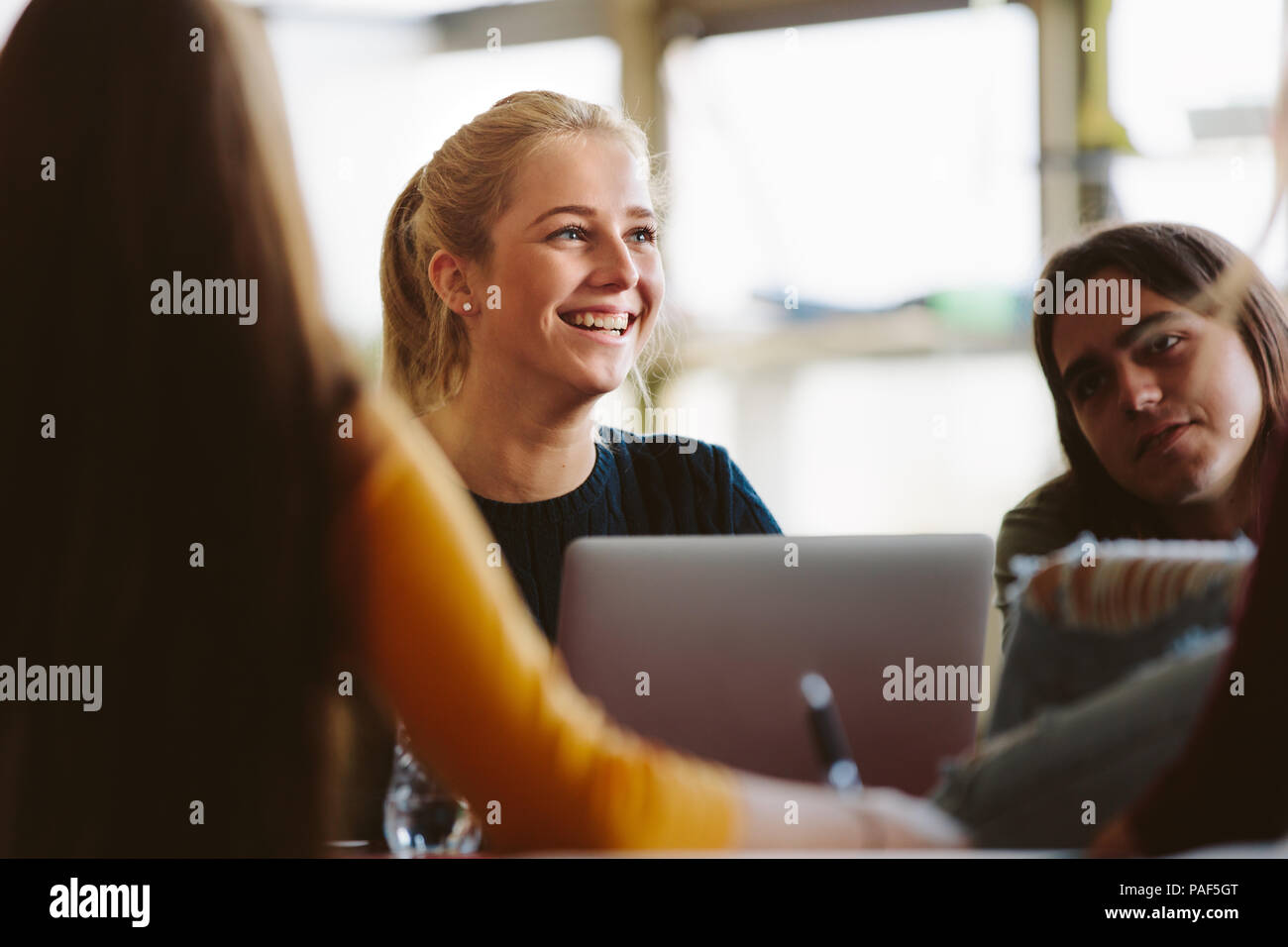 Studentessa seduta tra compagni di classe e sorridente in sala conferenze. studenti universitari in classe dopo la lezione. Foto Stock