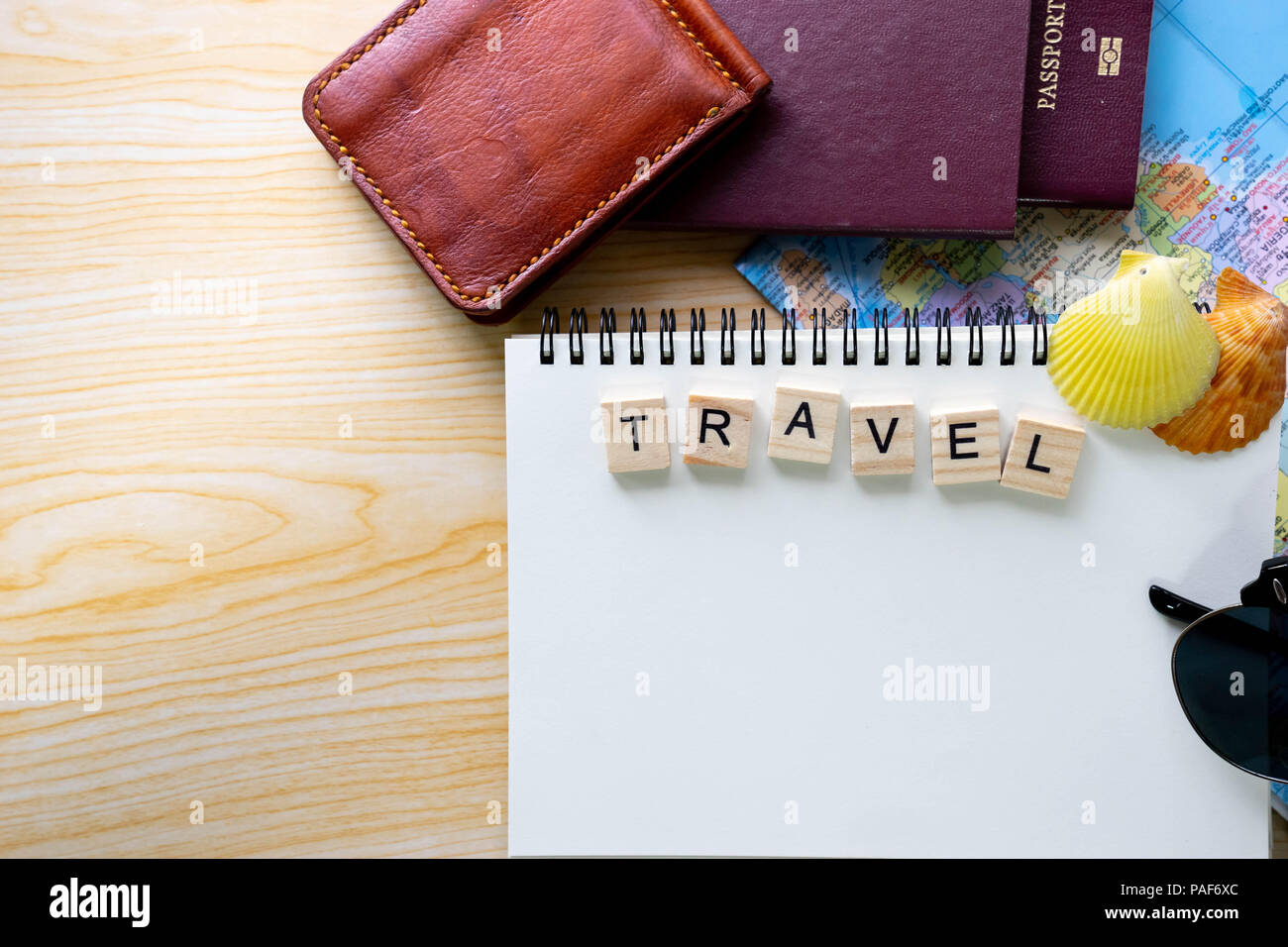 Piatto estivo laici parole scritte su legno blocco di Scrabble e accessori da viaggio su sfondo giallo con uno spazio vuoto per il testo. Vista dall'alto di viaggio o vaca Foto Stock