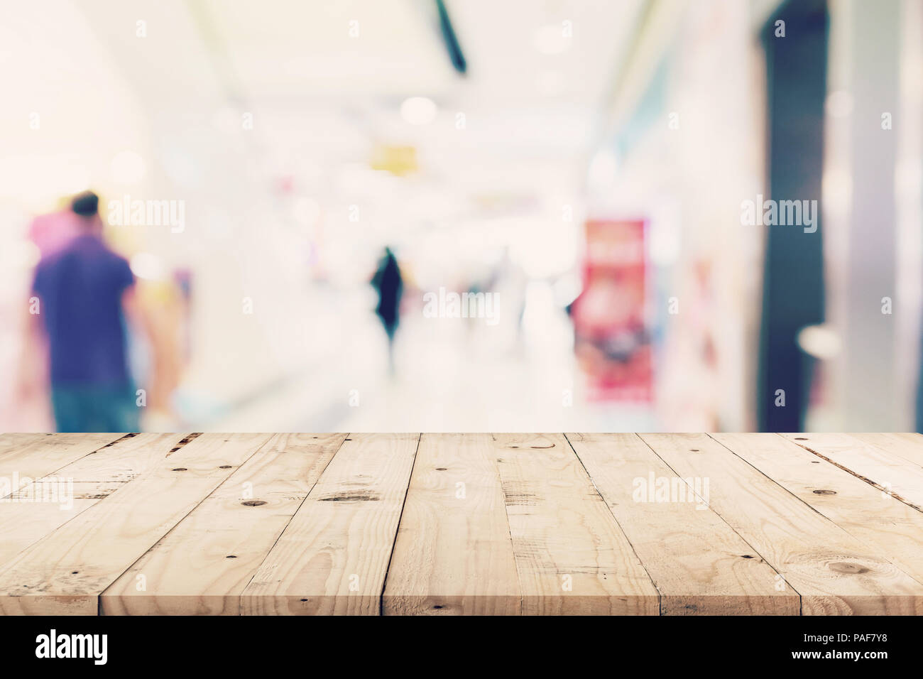 Svuotare tavolo in legno e sfondo sfocato - Store di shopping mall blur sullo sfondo bokeh con display montage per prodotto. Foto Stock