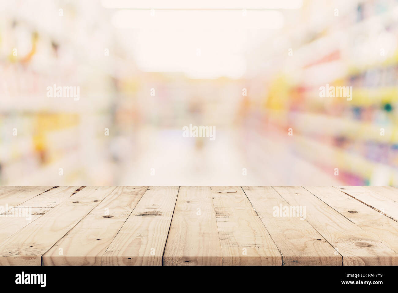 Svuotare tavolo in legno e sfondo sfocato - Store di shopping mall blur sullo sfondo bokeh con display montage per prodotto. Foto Stock