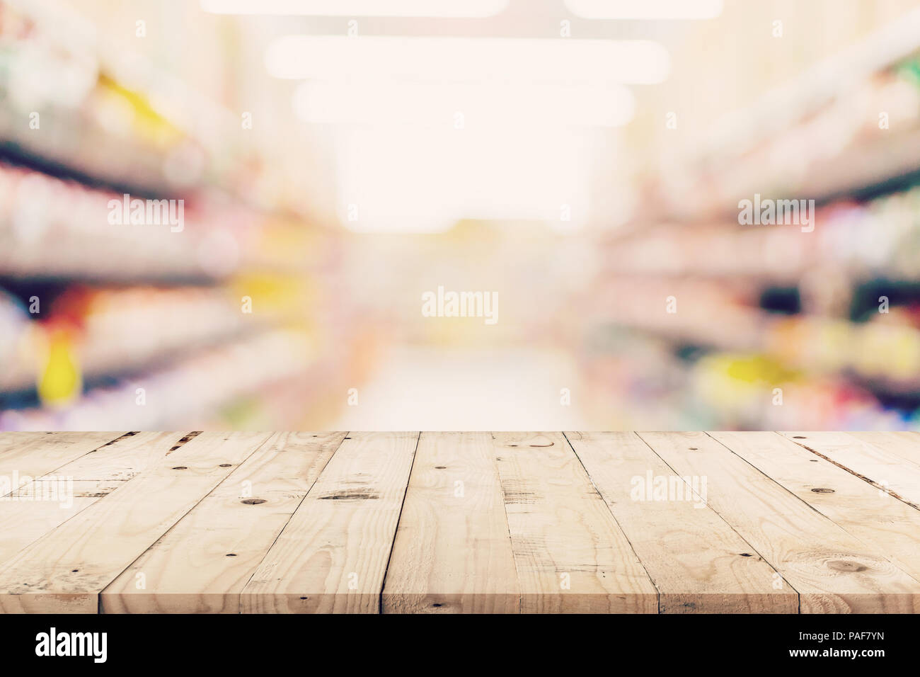 Svuotare tavolo in legno e sfondo sfocato - Store di shopping mall blur sullo sfondo bokeh con display montage per prodotto. Foto Stock