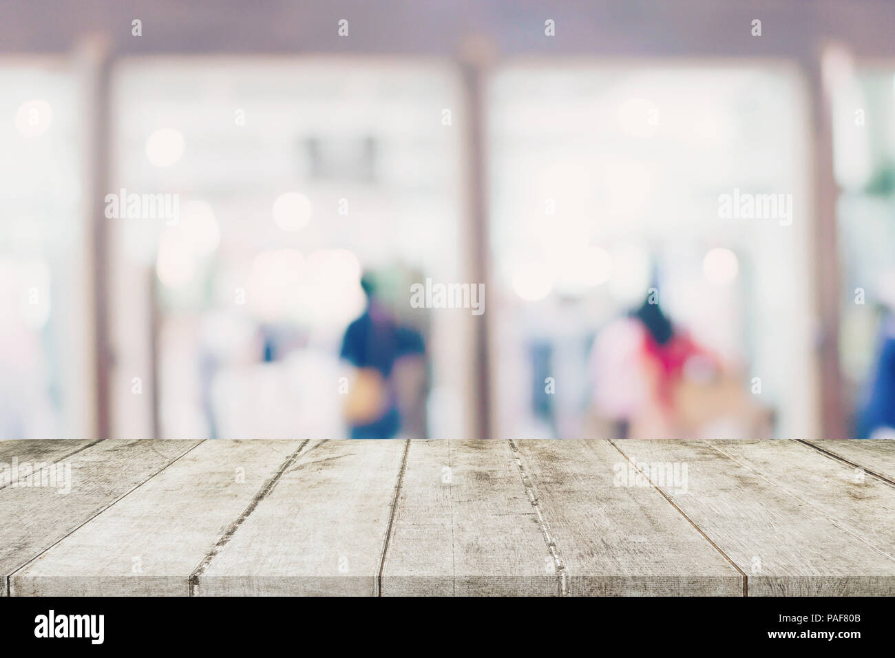 Svuotare tavolo in legno e sfondo sfocato - Store di shopping mall blur sullo sfondo bokeh con display montage per prodotto. Foto Stock