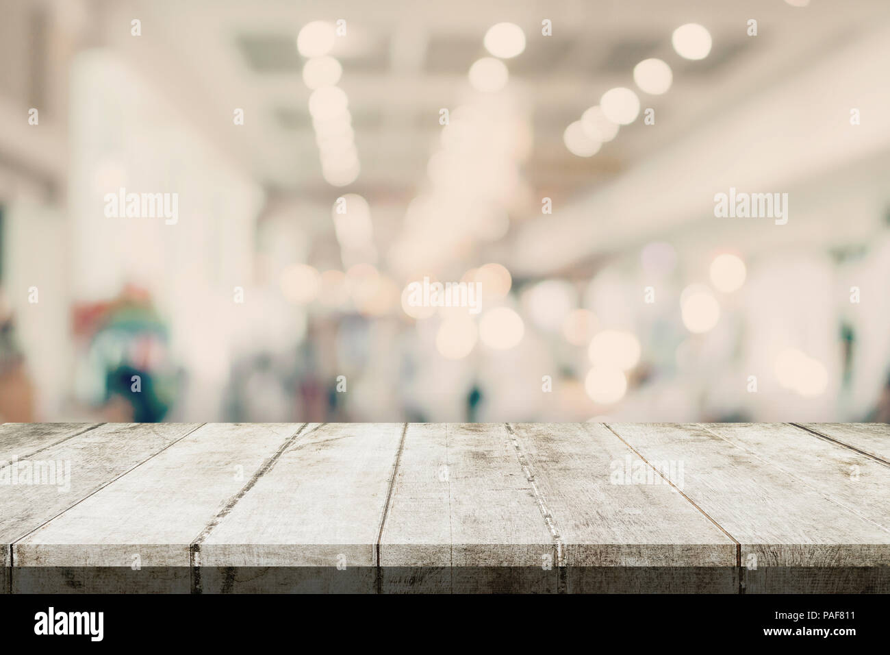 Svuotare tavolo in legno e sfondo sfocato - Store di shopping mall blur sullo sfondo bokeh con display montage per prodotto. Foto Stock