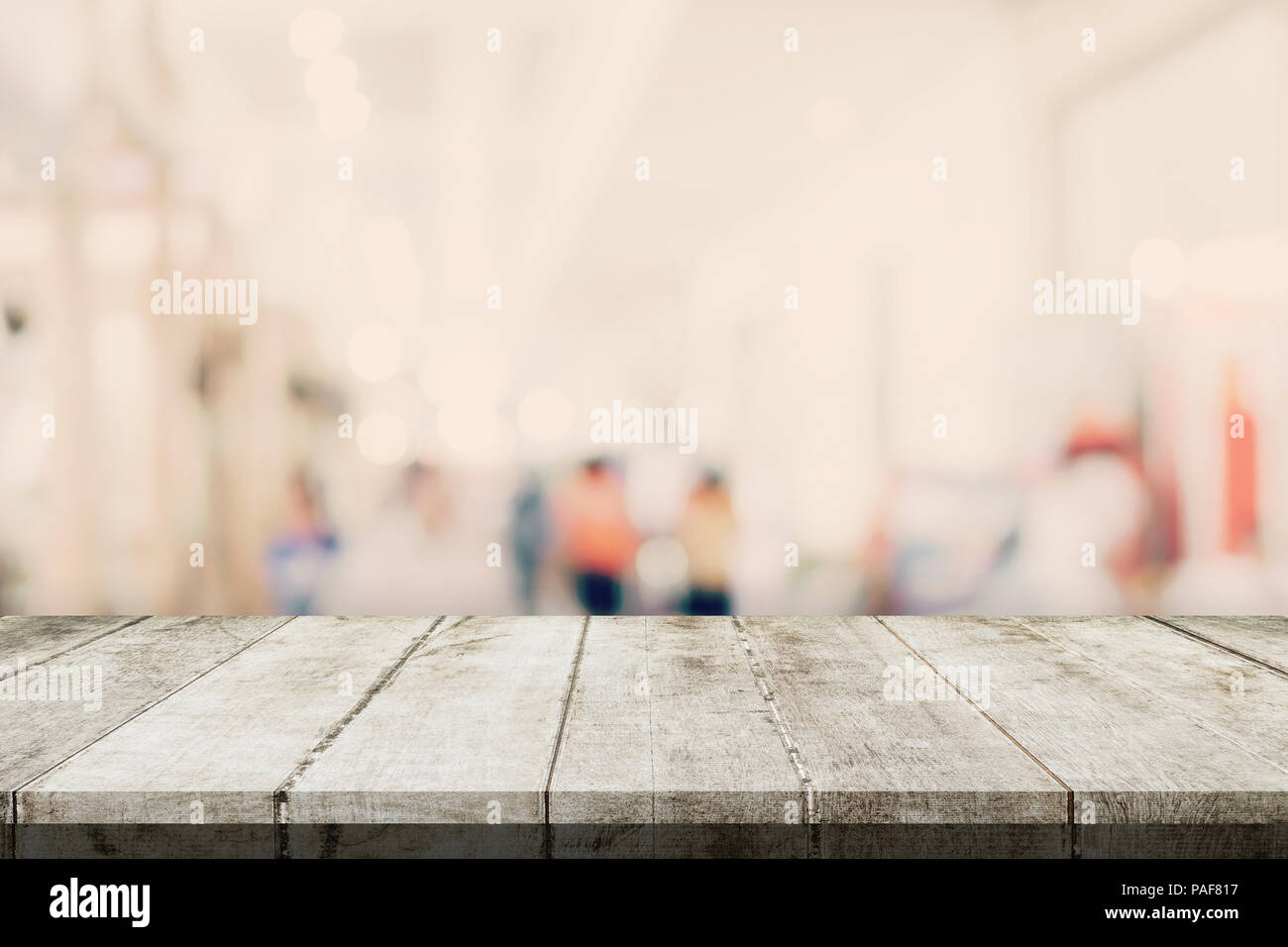 Svuotare tavolo in legno e sfondo sfocato - Store di shopping mall blur sullo sfondo bokeh con display montage per prodotto. Foto Stock