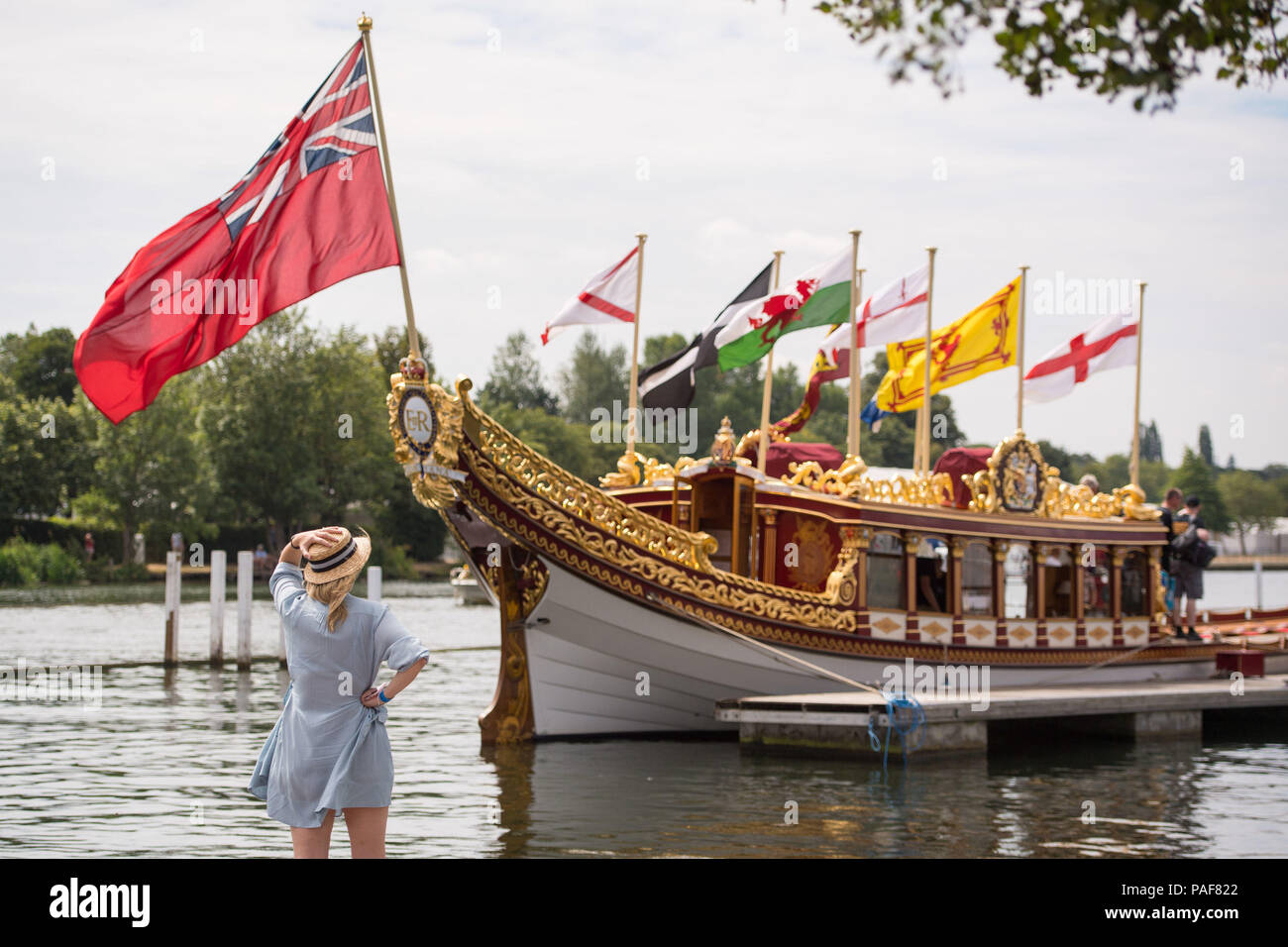 Un osservatore guarda la regina rowbarge "Vincenzo' come persone godetevi il clima mite durante il Tamigi barca tradizionale Festival a Henley on Thames, Oxfordshire. Foto Stock