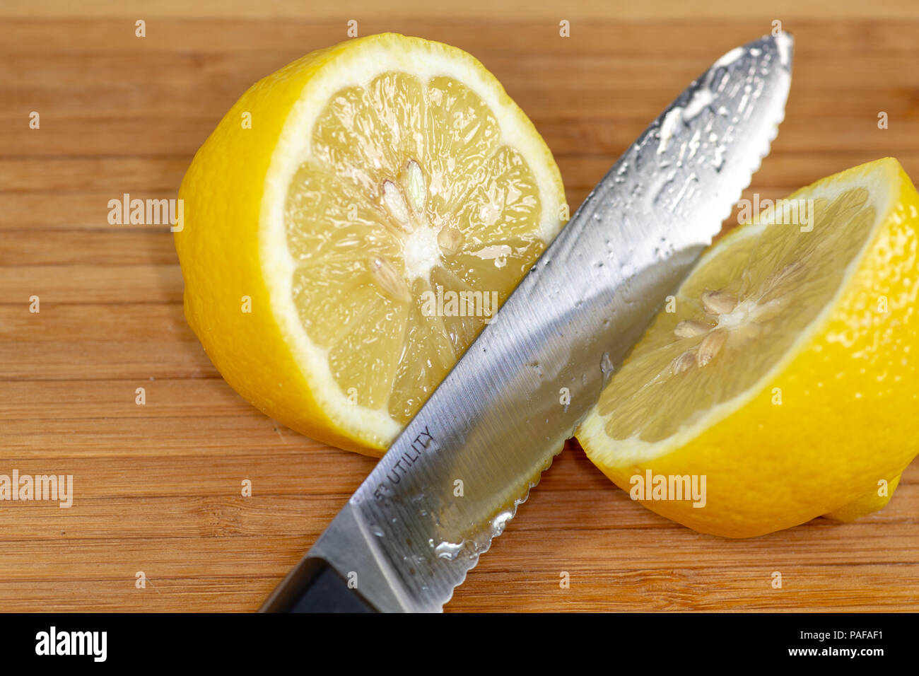 Il limone tagliato a metà lungo un bordo di taglio su un tavolo da cucina Foto Stock