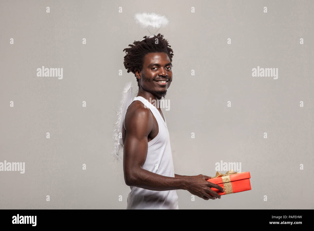 L uomo a nimbus e ali simile amore angel. dark scuoiati barbuto angelo africano funny man con una camicia bianca, nimbus e winks atanding e azienda gi Foto Stock