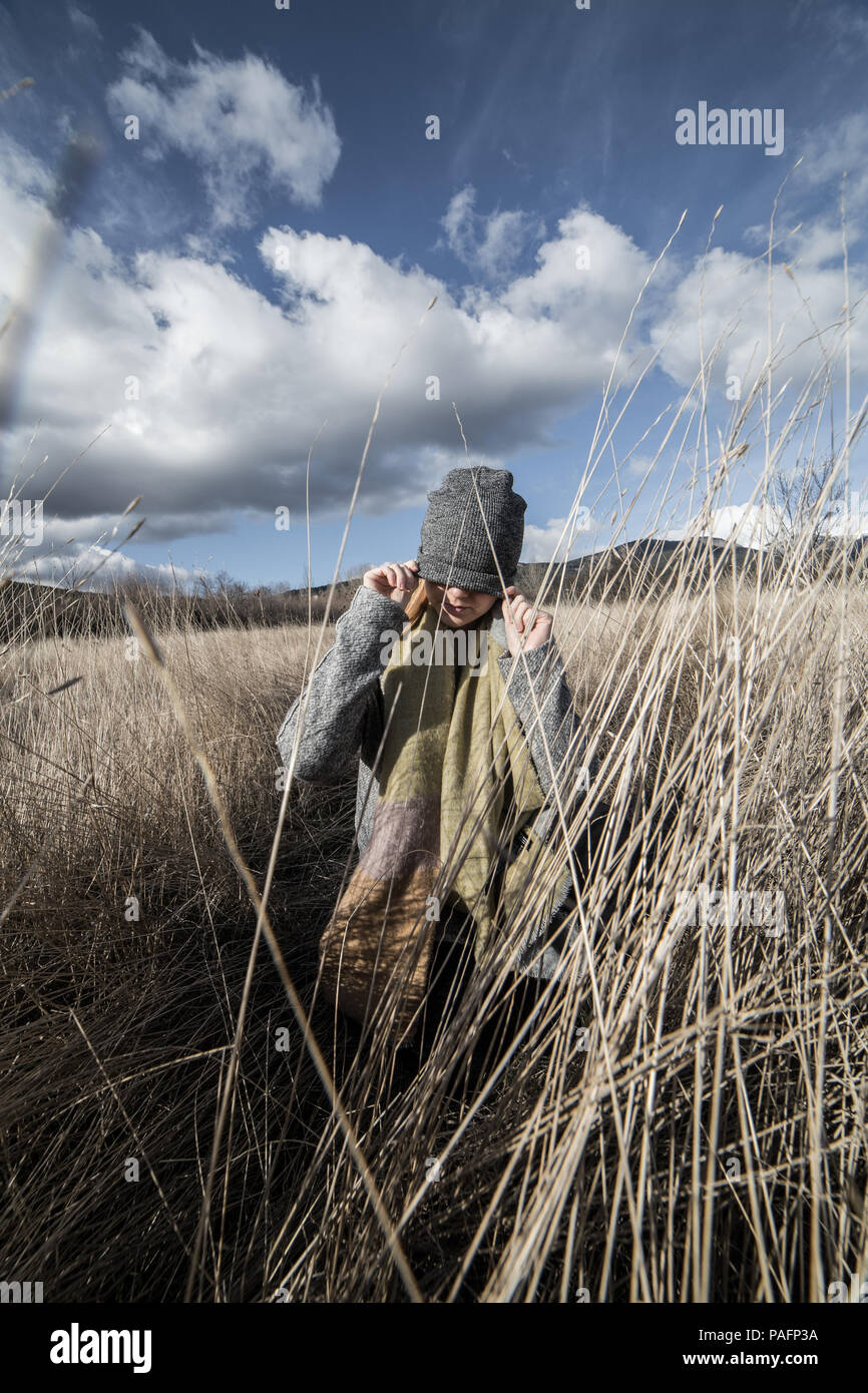 La donna in un secco campo di grano con gli occhi coperti con un tappo grigio Foto Stock