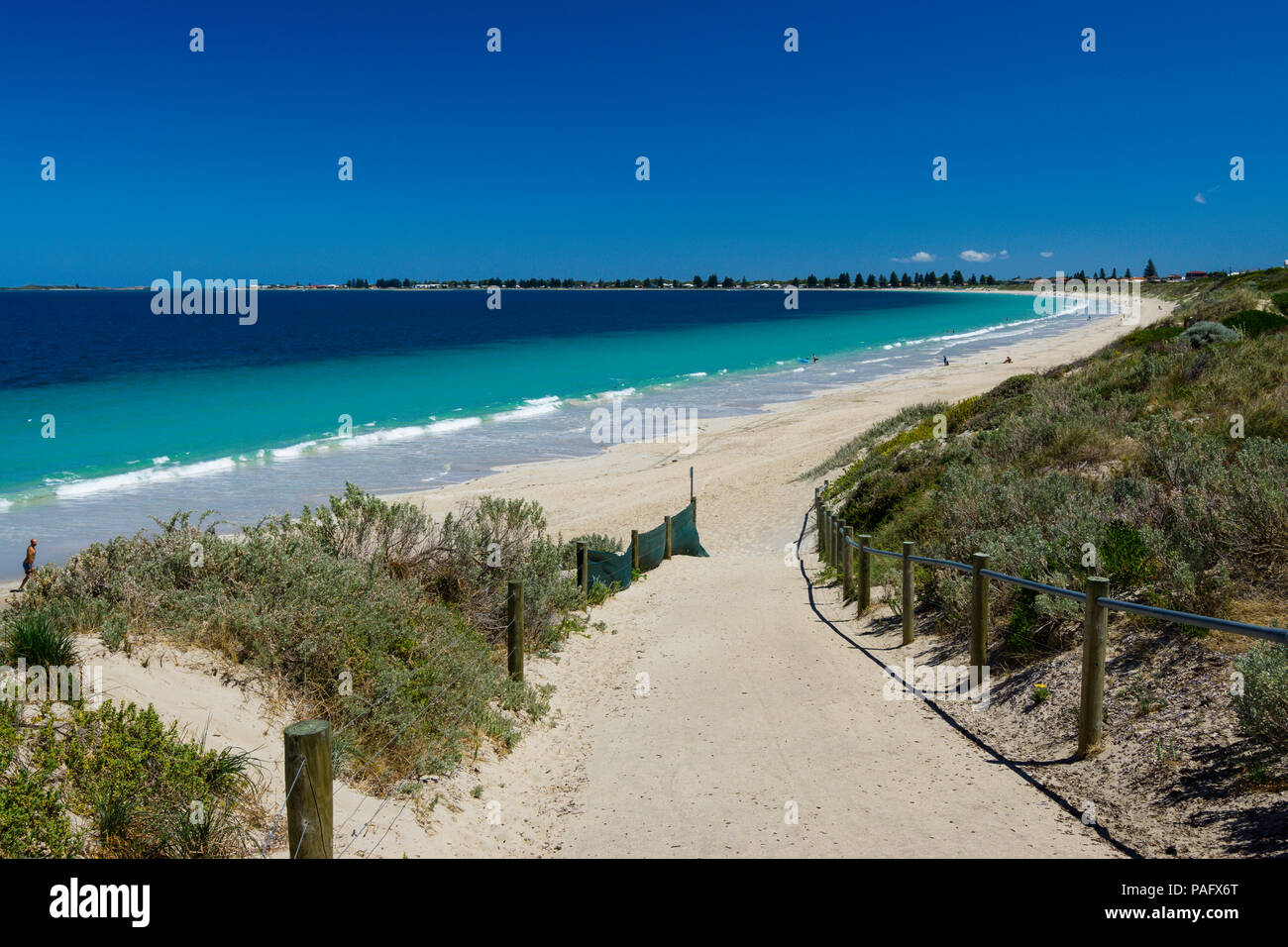 Sentiero di sabbia che conduce giù per deserta spiaggia di sabbia bianca con chiare acque blu sulla giornata d'estate Foto Stock