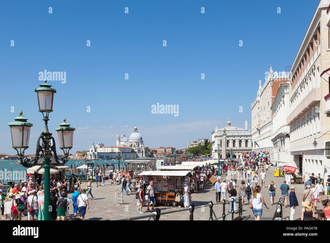 Turisti e chioschi di souvenir Riva degli Schiavonni, San Marco, Venezia, Veneto, Italia. Vista in elevazione a Basilica di Santa Maria della Salute Foto Stock