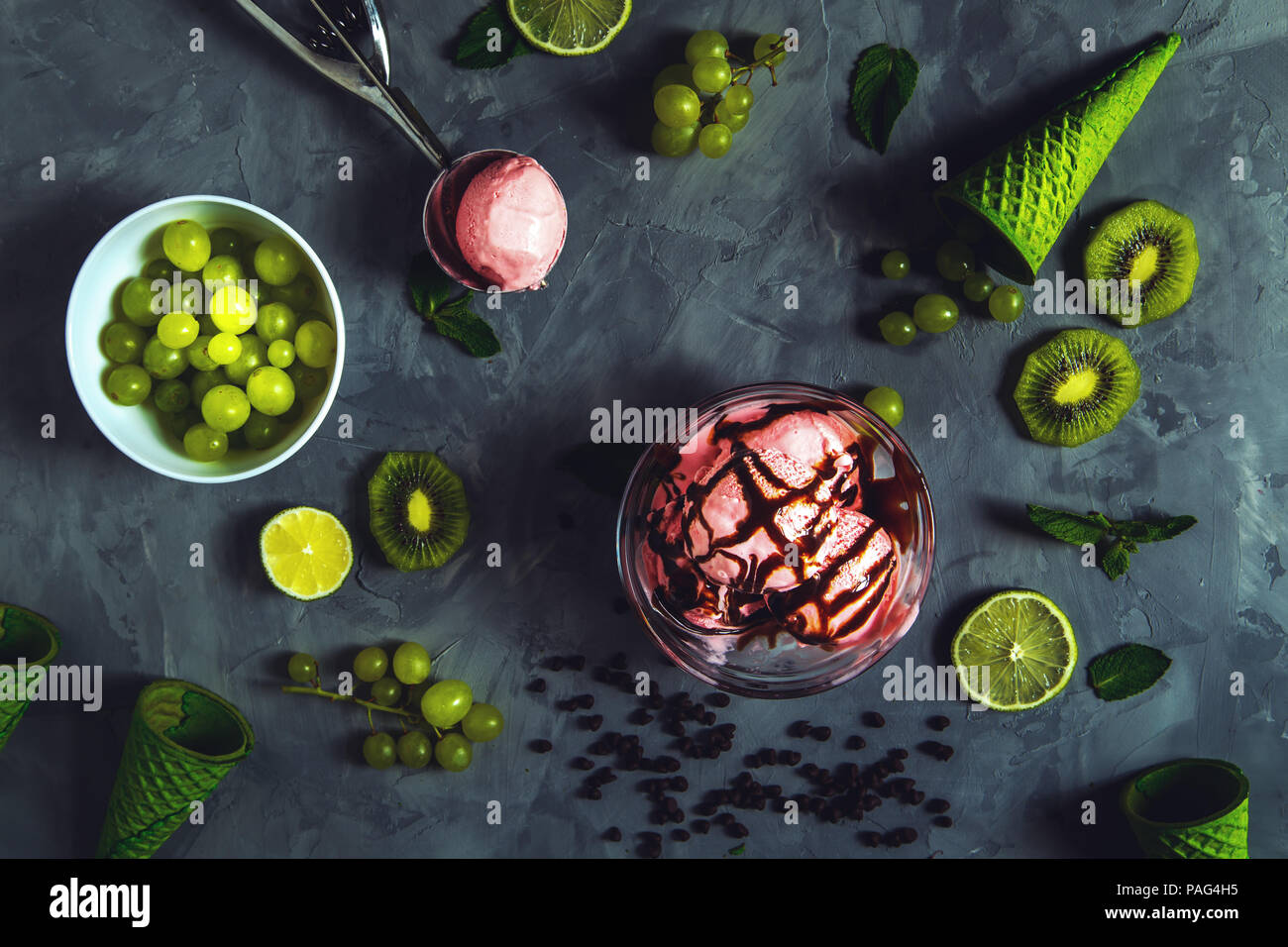 Gelato alla fragola con diversi frutti di bosco e menta su sfondo grigio. Foto Stock