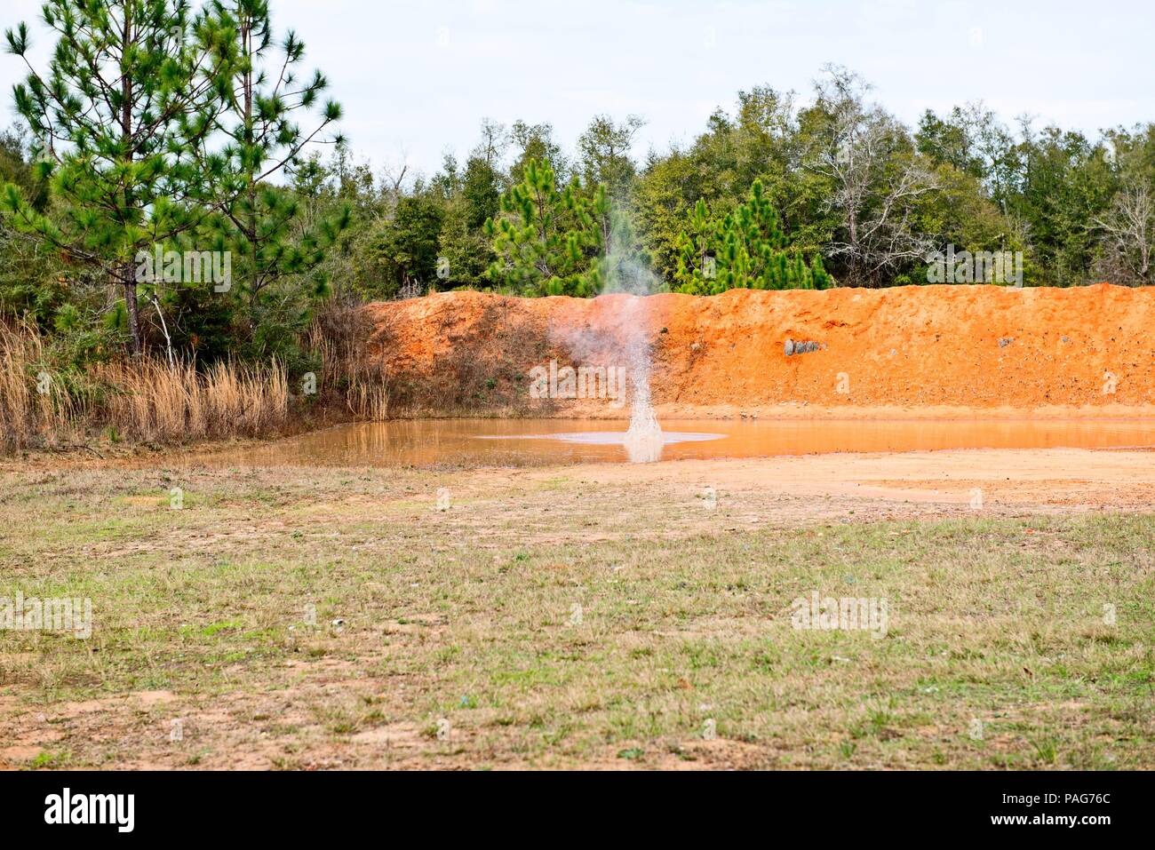 Gli spruzzi di acqua in rosso grande pozza di argilla Foto Stock