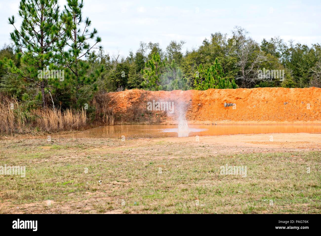 Gli spruzzi di acqua in rosso grande pozza di argilla Foto Stock