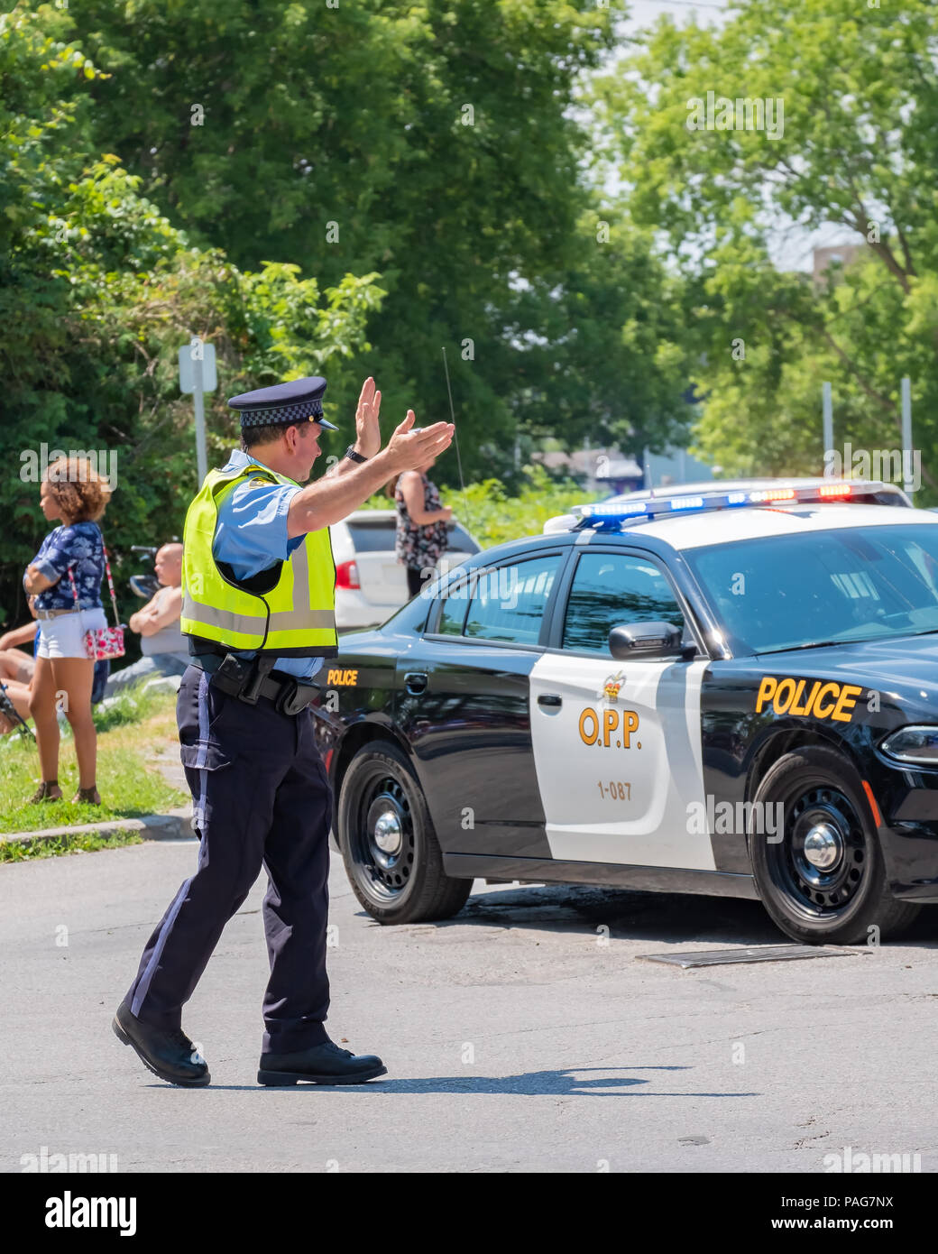 Ausiliario per un funzionario di polizia dirige il traffico su una strada trafficata durante un evento in Orillia Ontario. Foto Stock