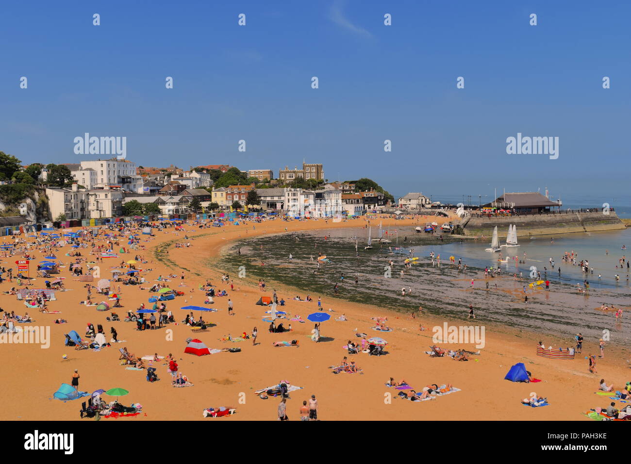 Inghilterra, Broadstairs. Pranzo Spiaggia con sun bagnanti durante la canicola estiva. Porto in background. Broadstairs, Kent, Regno Unito, Luglio 2018 Foto Stock