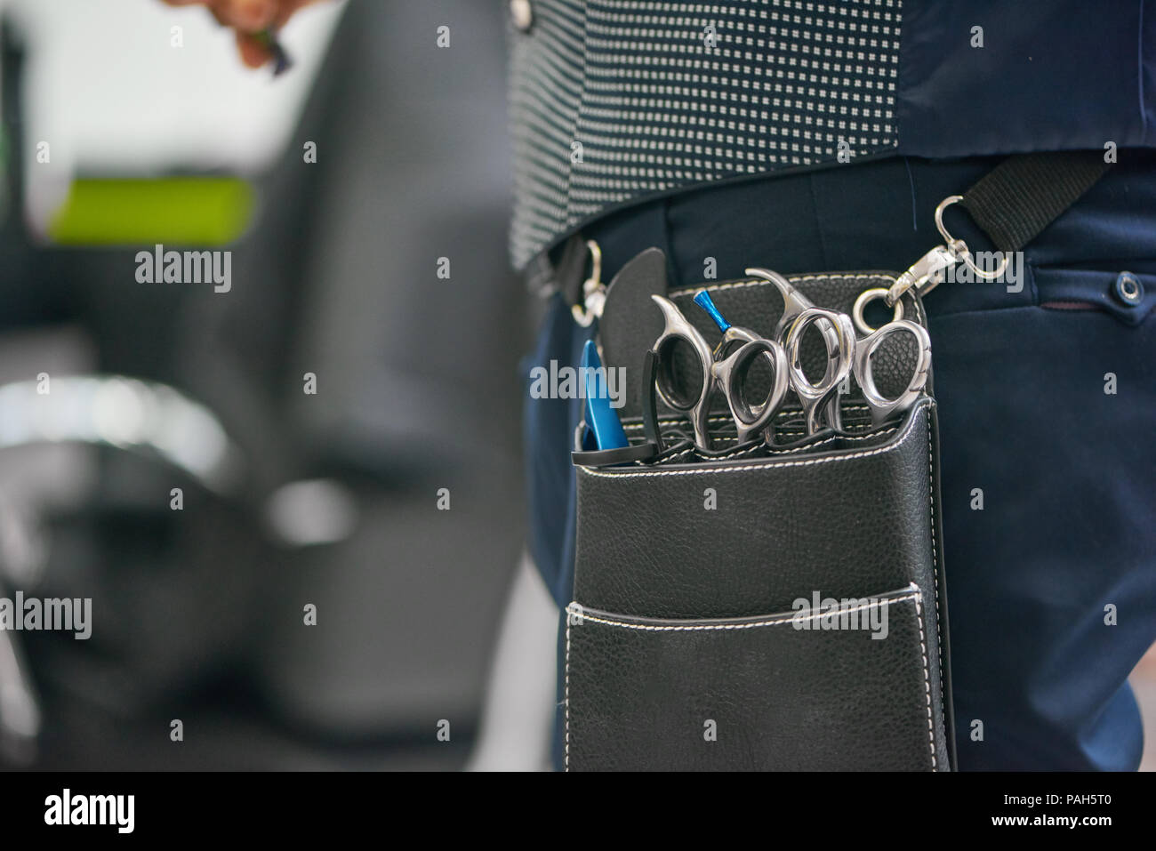 Chiusura del barbiere di borsa in pelle metallica con taglienti forbici appeso alla cintola. Apparecchio indossando blu scuro Pantaloni Gilet grigio. Andare a lavorare con il cliente in attesa di nuovi copricapo. Foto Stock