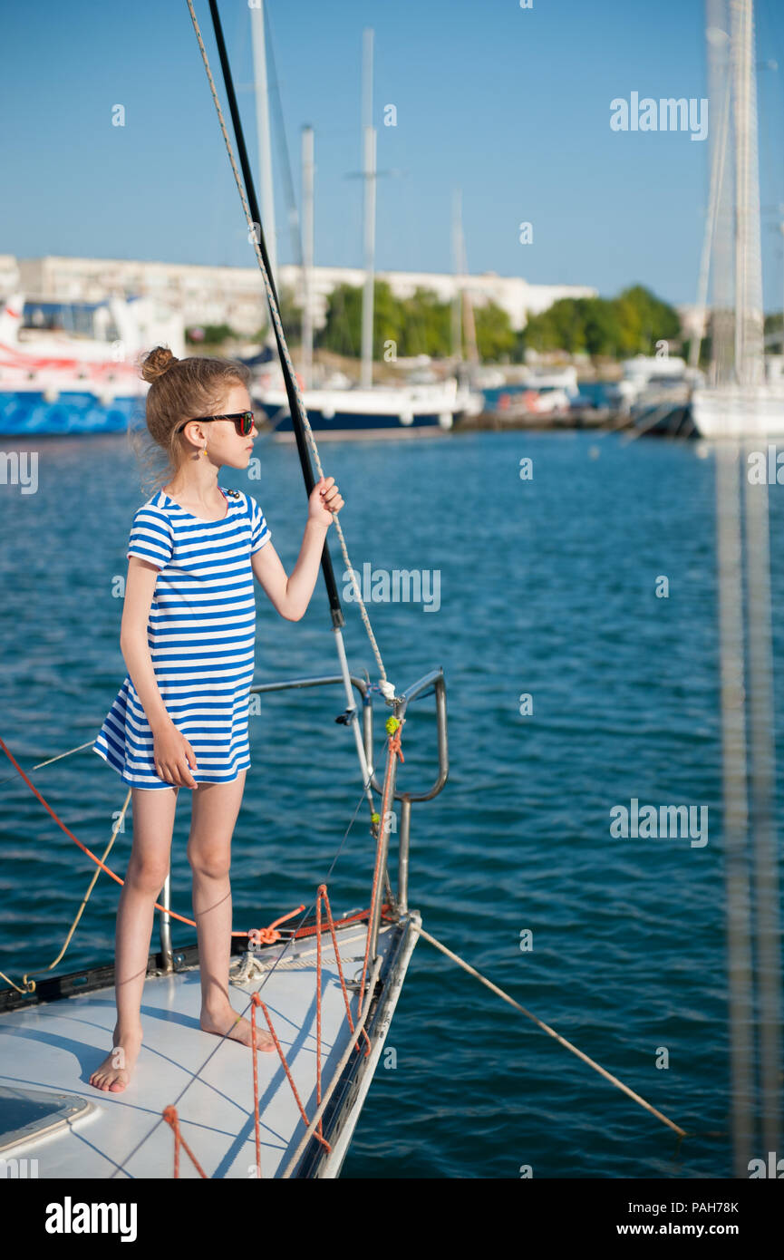 Bellissima bambina in camicia a righe e occhiali da sole su yacht di lusso board Foto Stock