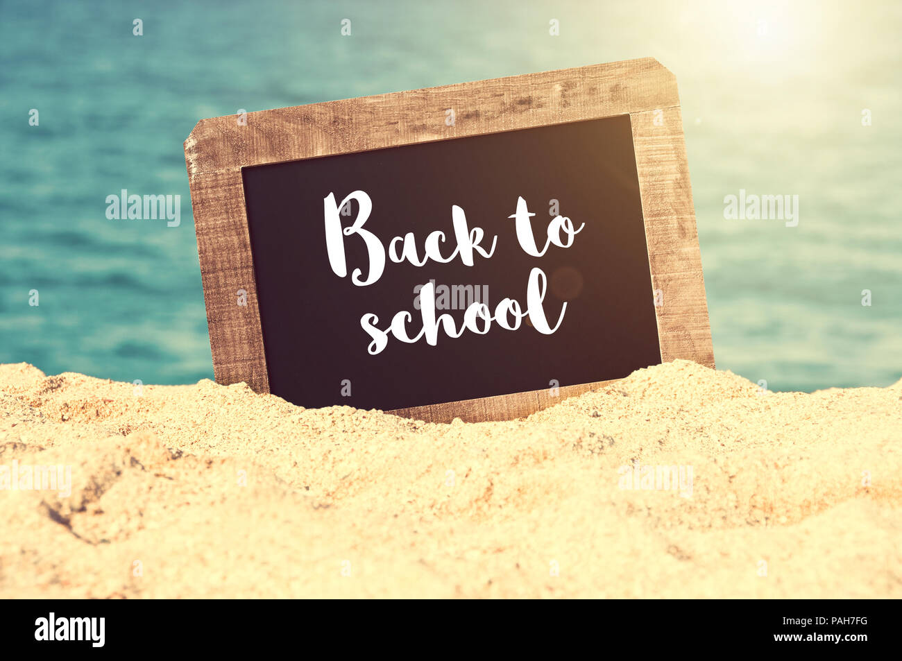 Si torna a scuola scritto su una lavagna vintage nella sabbia di una spiaggia Foto Stock