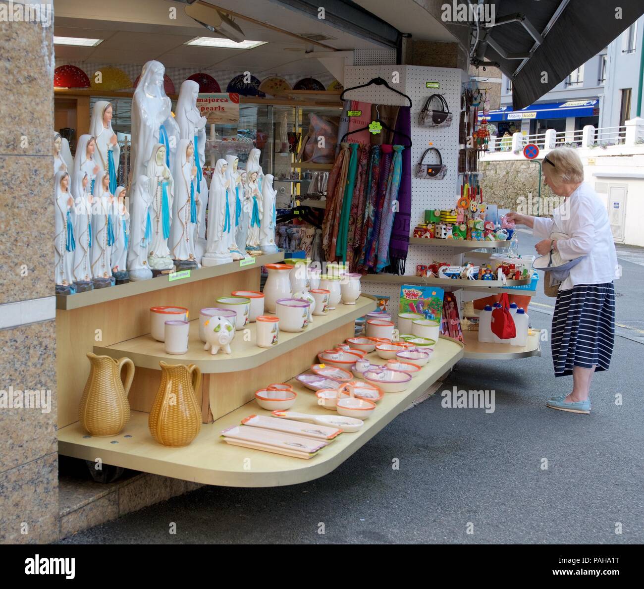 Un pellegrino guarda in un negozio di souvenir a Lourdes, Hautes Pirenei, Francia Foto Stock