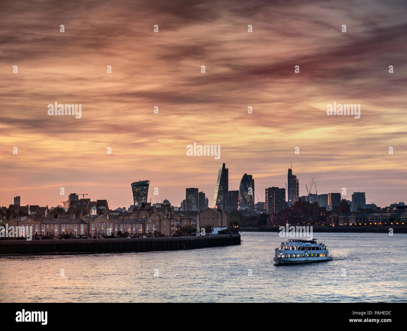 Londra città finanziaria vista skyline visto da Canary Wharf con una crociera sul fiume in barca per il tempo libero in primo piano al tramonto London EC1 Foto Stock