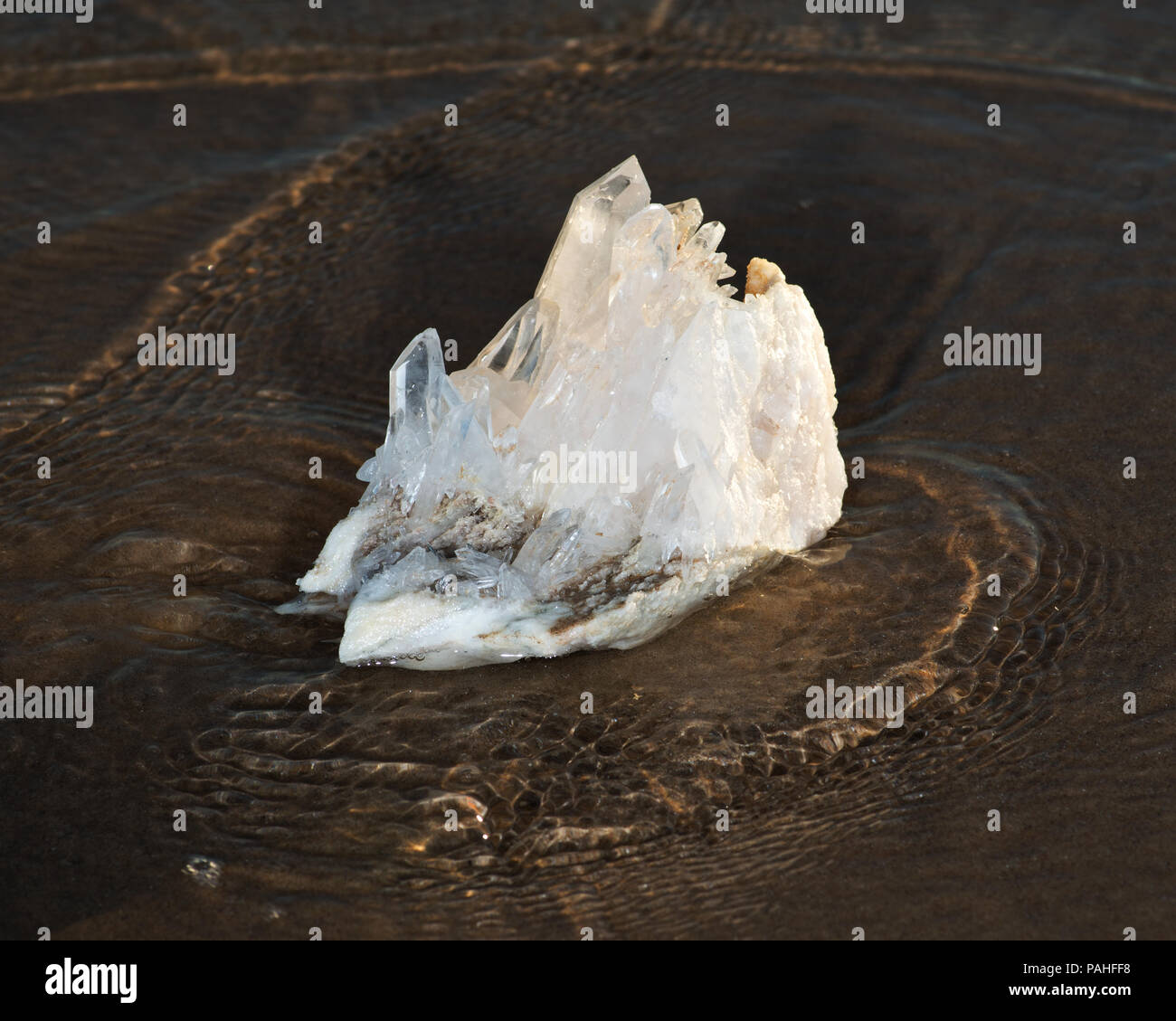 L'Himalayan quarzo trasparente Cluster Laser sulla sabbia bagnata in prossimità dell'acqua sulla spiaggia di sunrise. Foto Stock