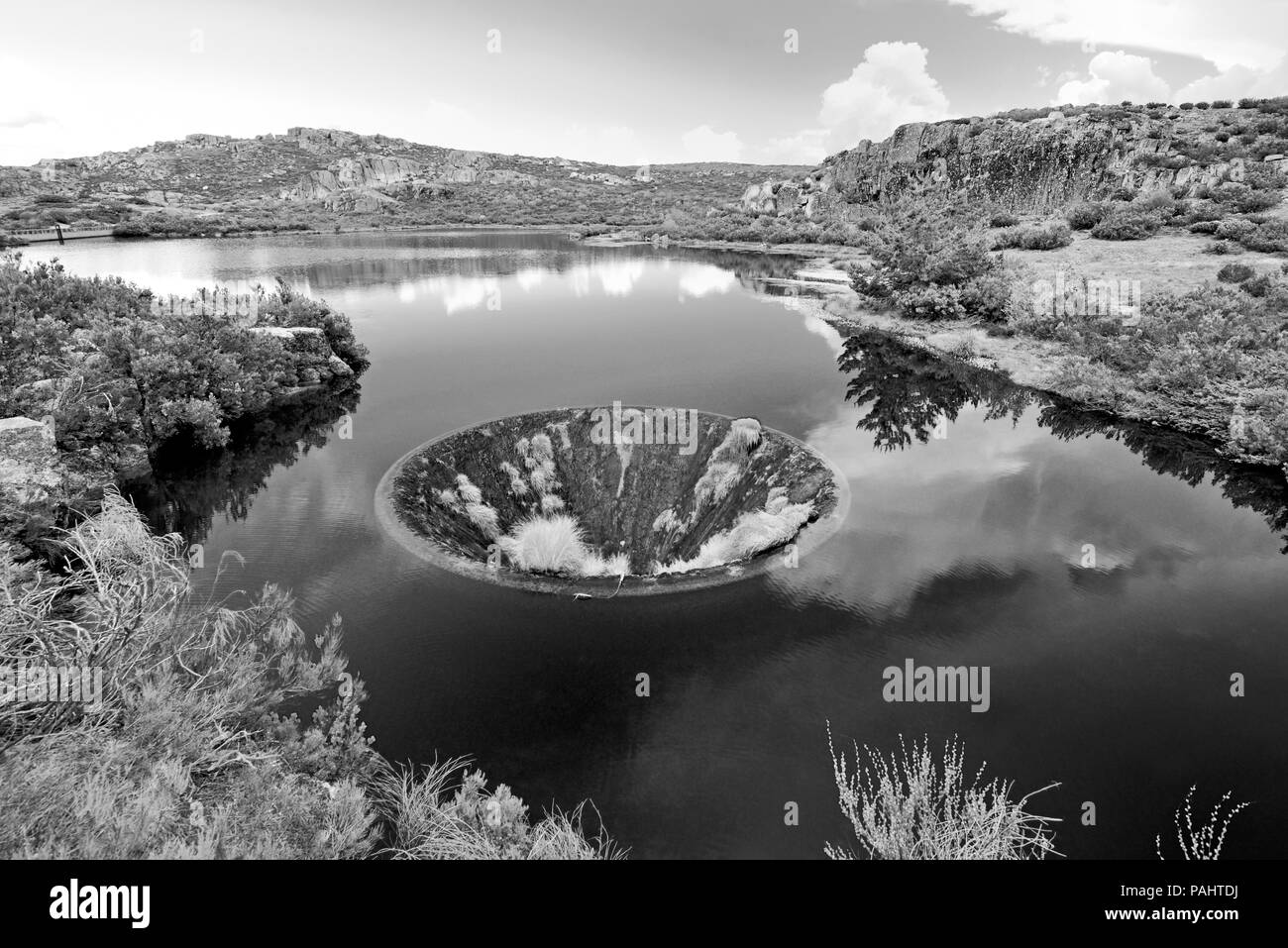 L'uomo ha fatto imbuto nel mezzo di un lago di montagna in bianco e nero Foto Stock
