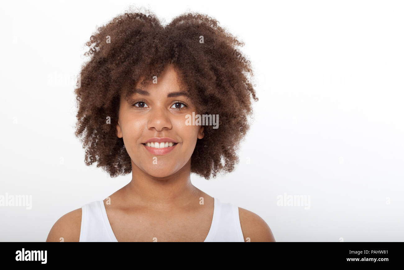 Ritratto di bella americano africano modello femminile sorridente isolato su bianco. Attraente bruna di carnagione scura donna in un bianco serbatoio superiore. Foto Stock