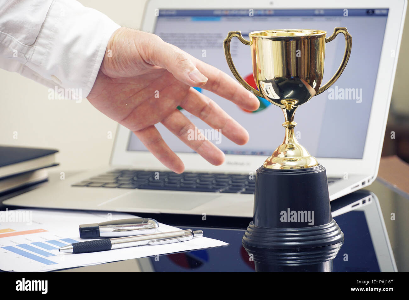 Imprenditore 's mano afferra i trofei, win concetto. Foto Stock