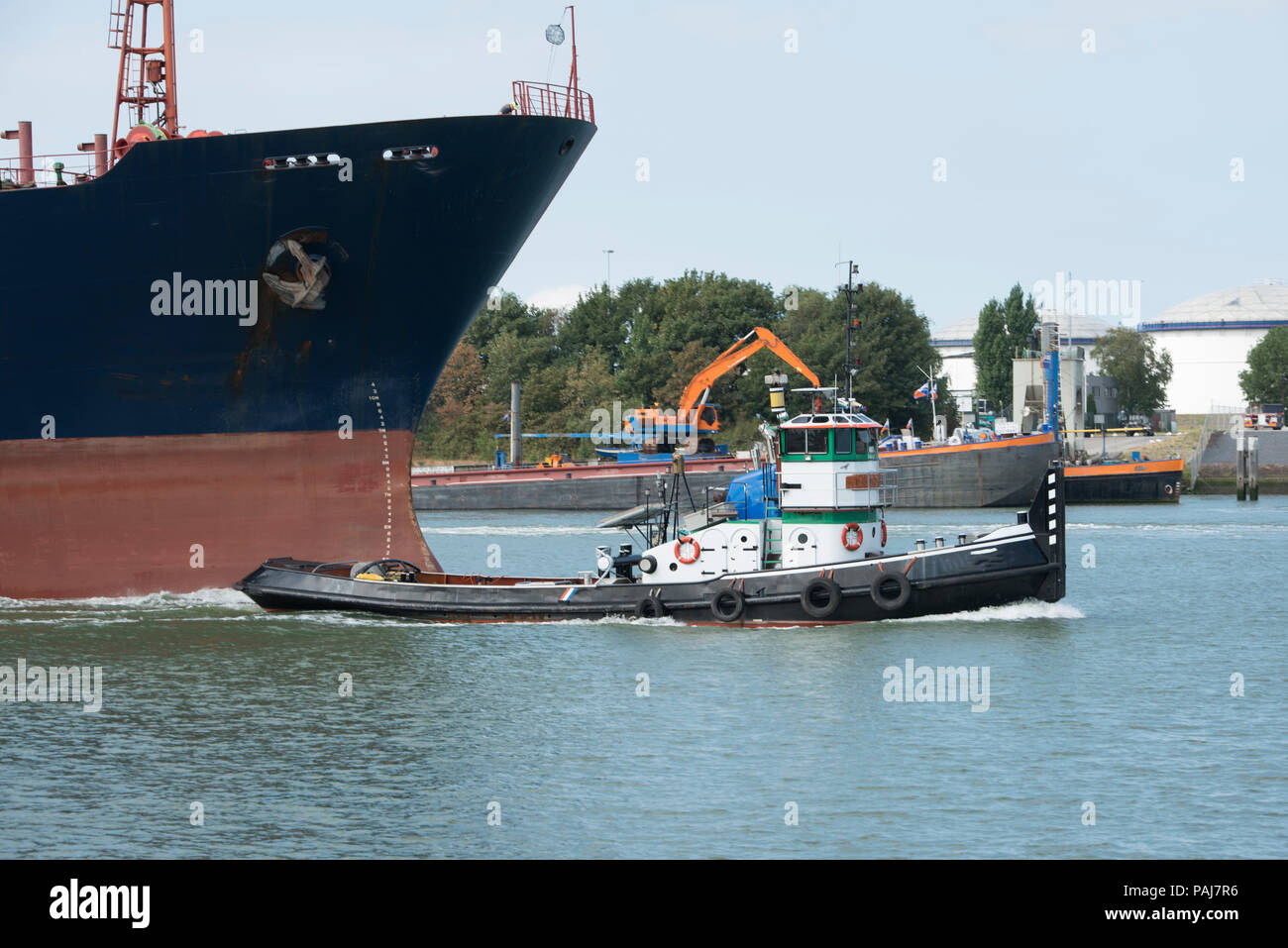 Piccolo rimorchiatore rilasciare i cavi dopo aver tirato la grande nave attraverso il fiume Maas in Olanda Foto Stock